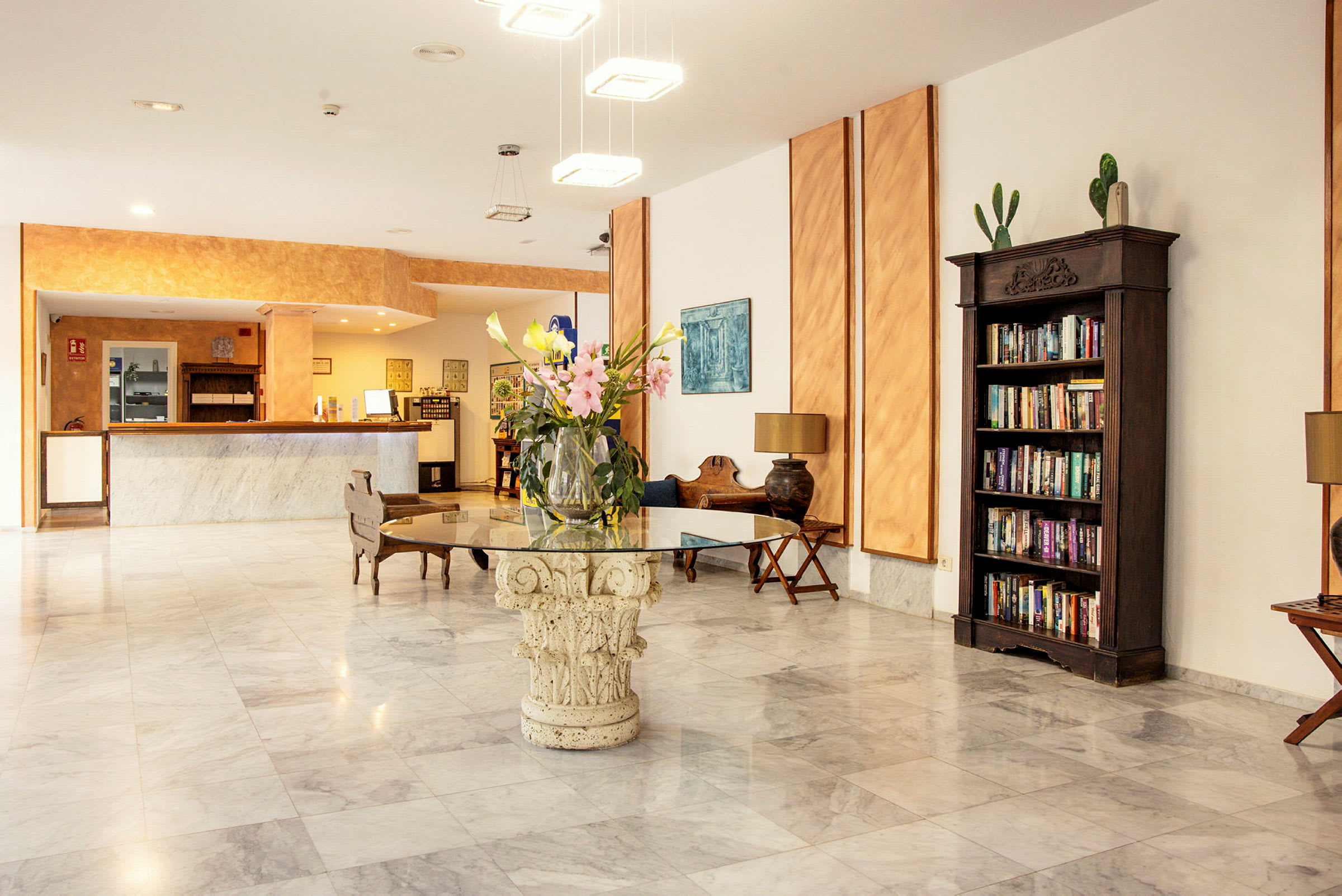 Hotellobby med receptionsskrivebord, blomsterbuket på et bord og bogreol. (AI-genereret tekst)