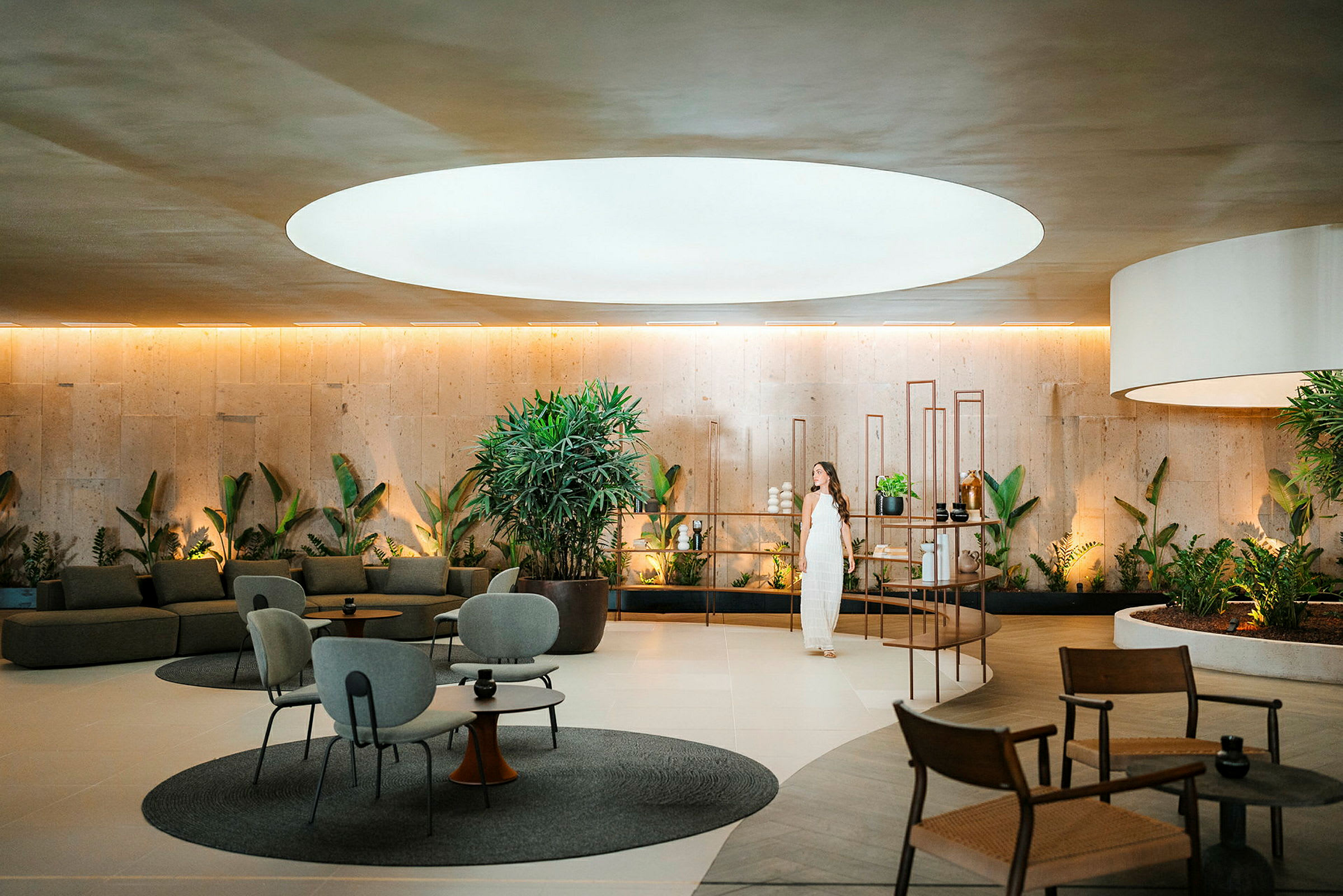 En moderne lounge med planter, siddepladser og stor lysåbning i loftet. (AI-genereret tekst)