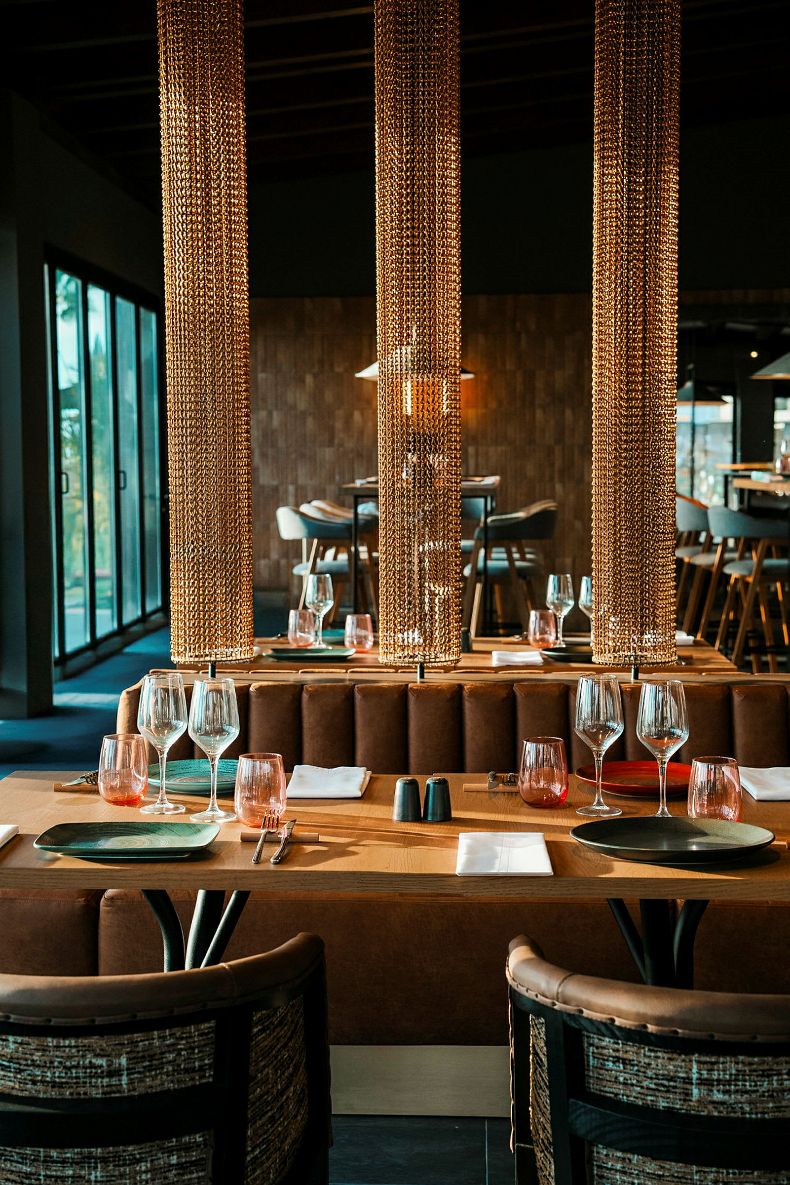 Et elegant restaurantbord med rustikke detaljer, dækket med vinglas og tallerkener, omgivet af dekorative kæder. (AI-genereret tekst)