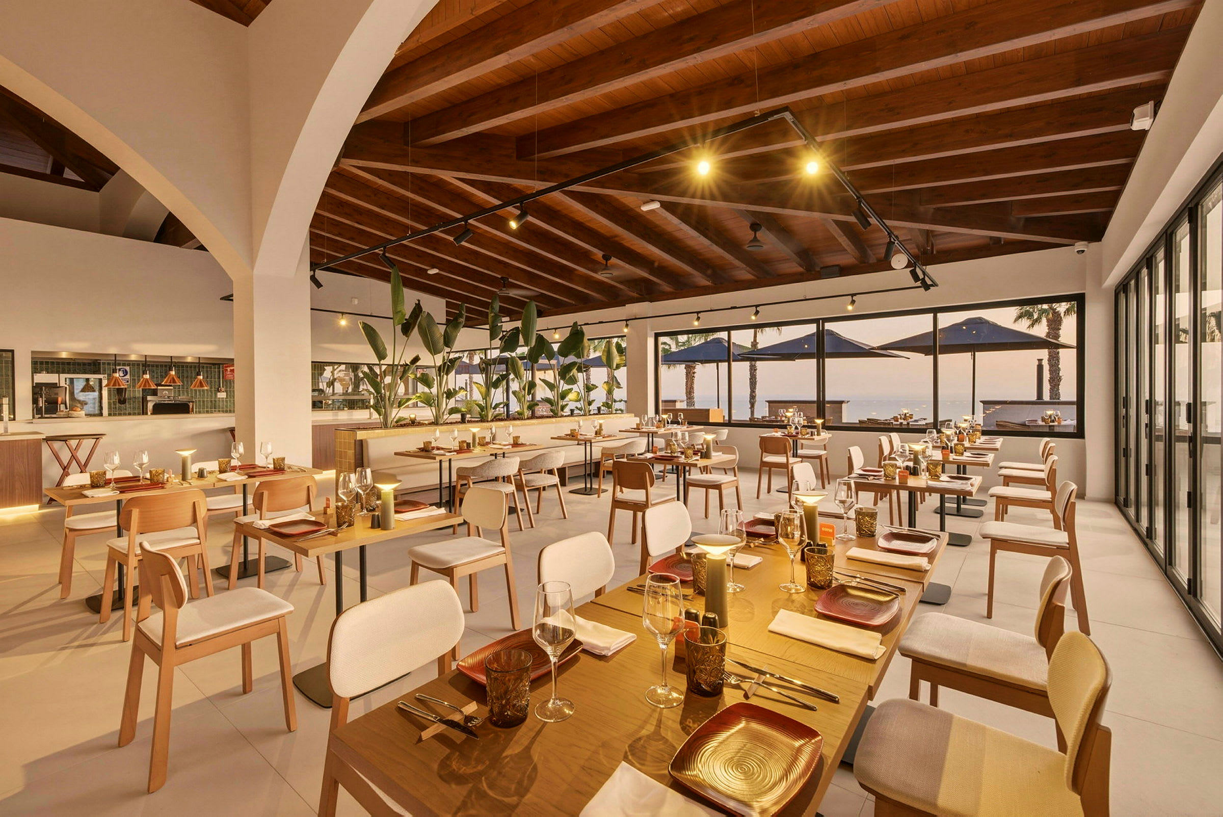 En elegant restaurant med flere siddepladser, store vinduer med udsigt og en velbelyst atmosfære med moderne design. (AI-genereret tekst)
