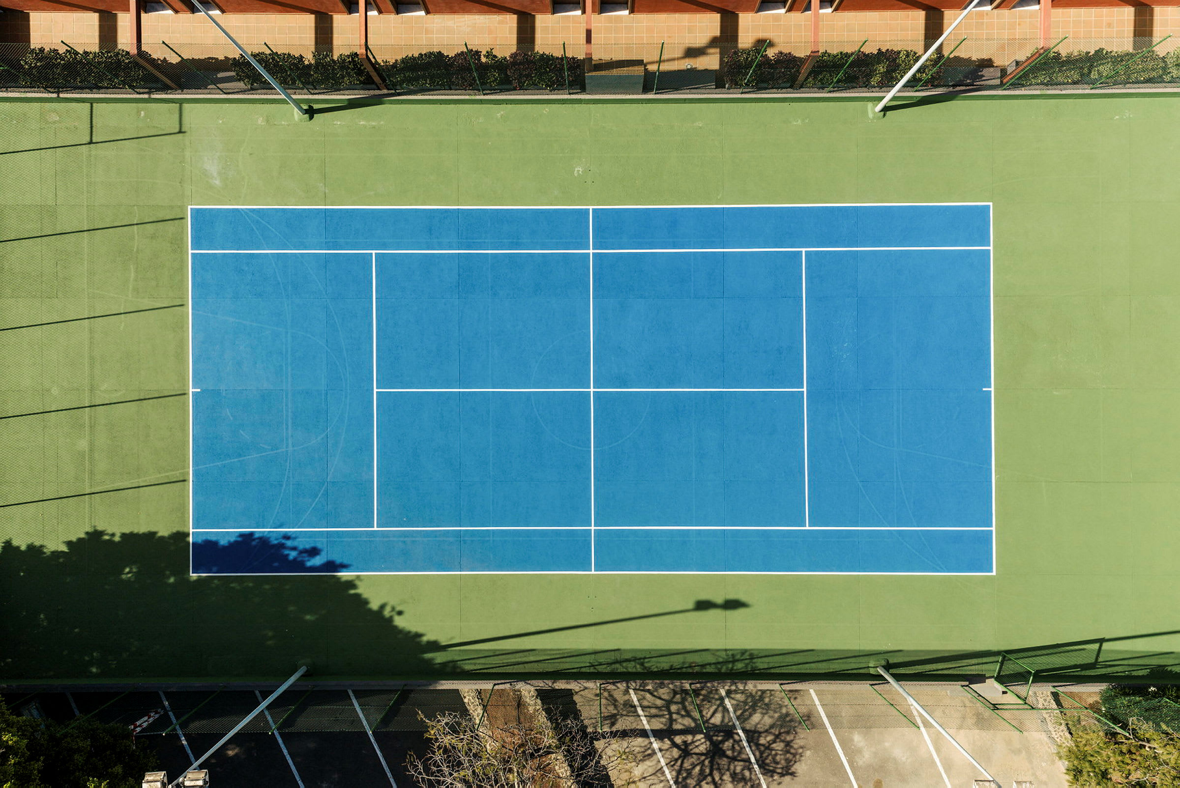 Et fugleperspektivbillede af en tennisbane med blå bane og grønne kanter. (AI-genereret tekst)