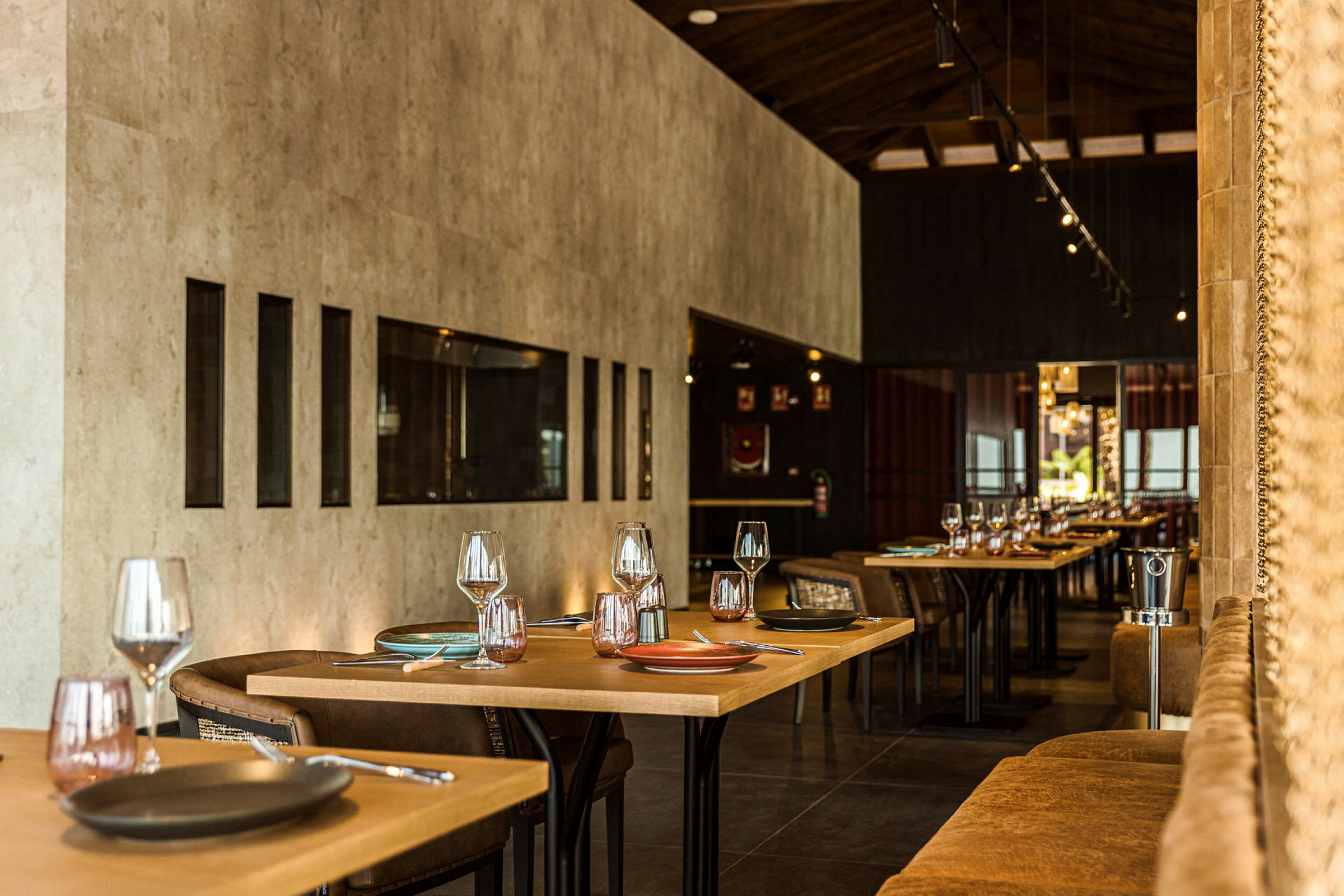 Et moderne og elegant indrettet restaurantinteriør med dækkede borde og stole arrangeret i en varm atmosfære. (AI-genereret tekst)