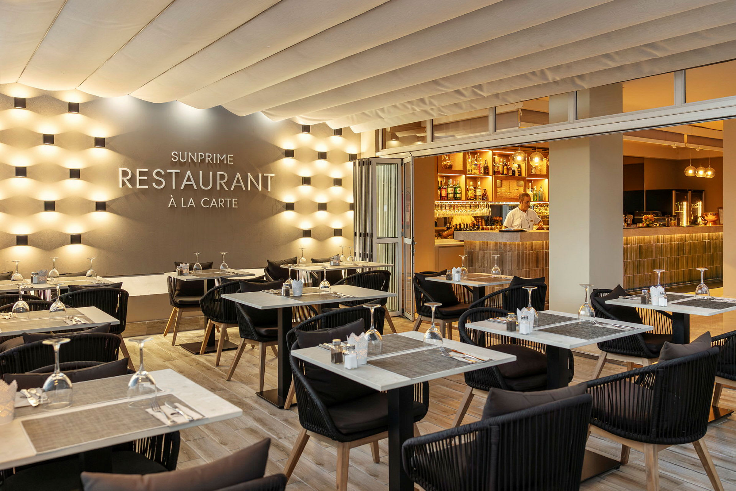 En elegant restaurantlokale med dækkede borde og en oplyst bar. (AI-genereret tekst)