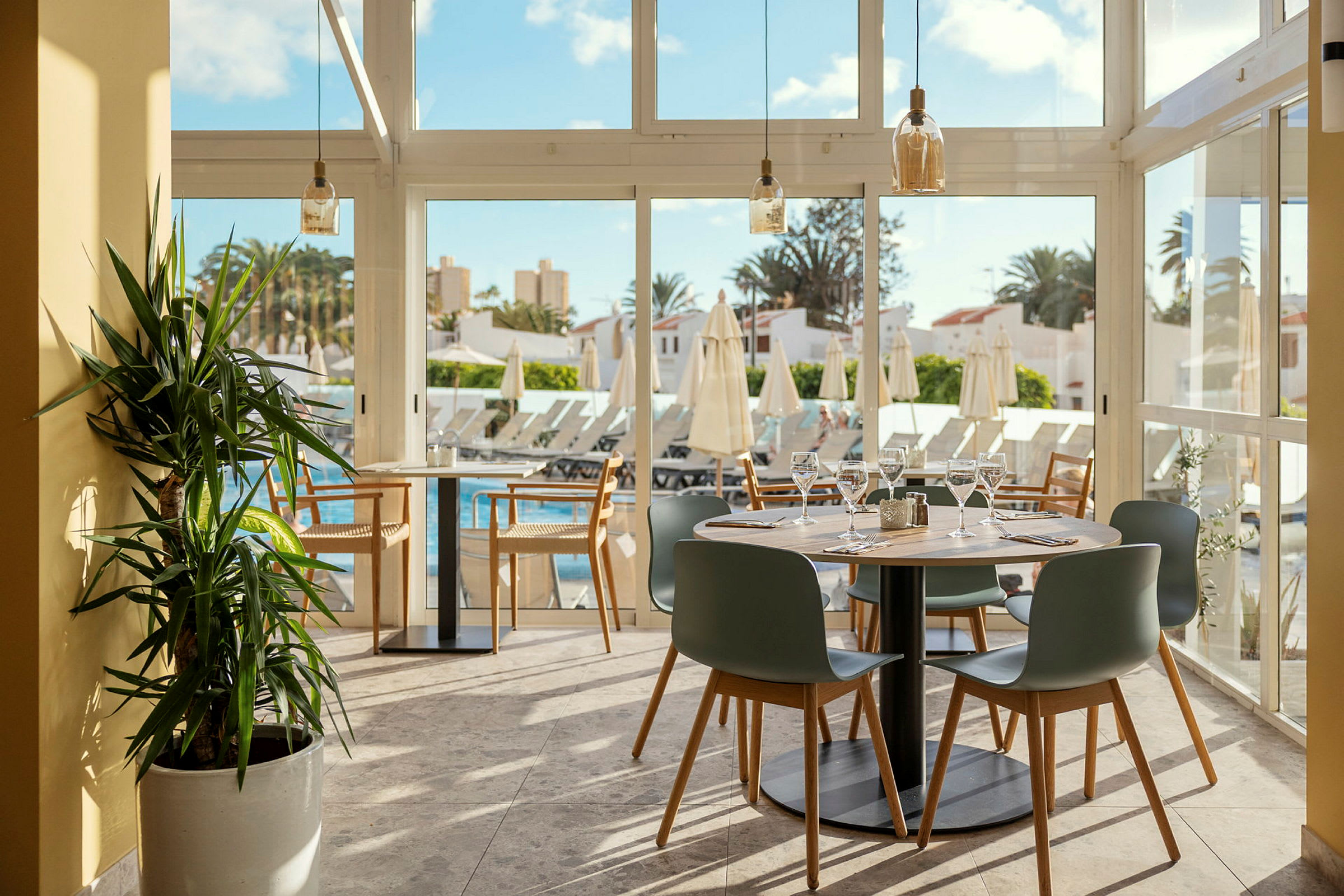 Restaurant med dækkede borde og udsigt over pool og liggestole. (AI-genereret tekst)