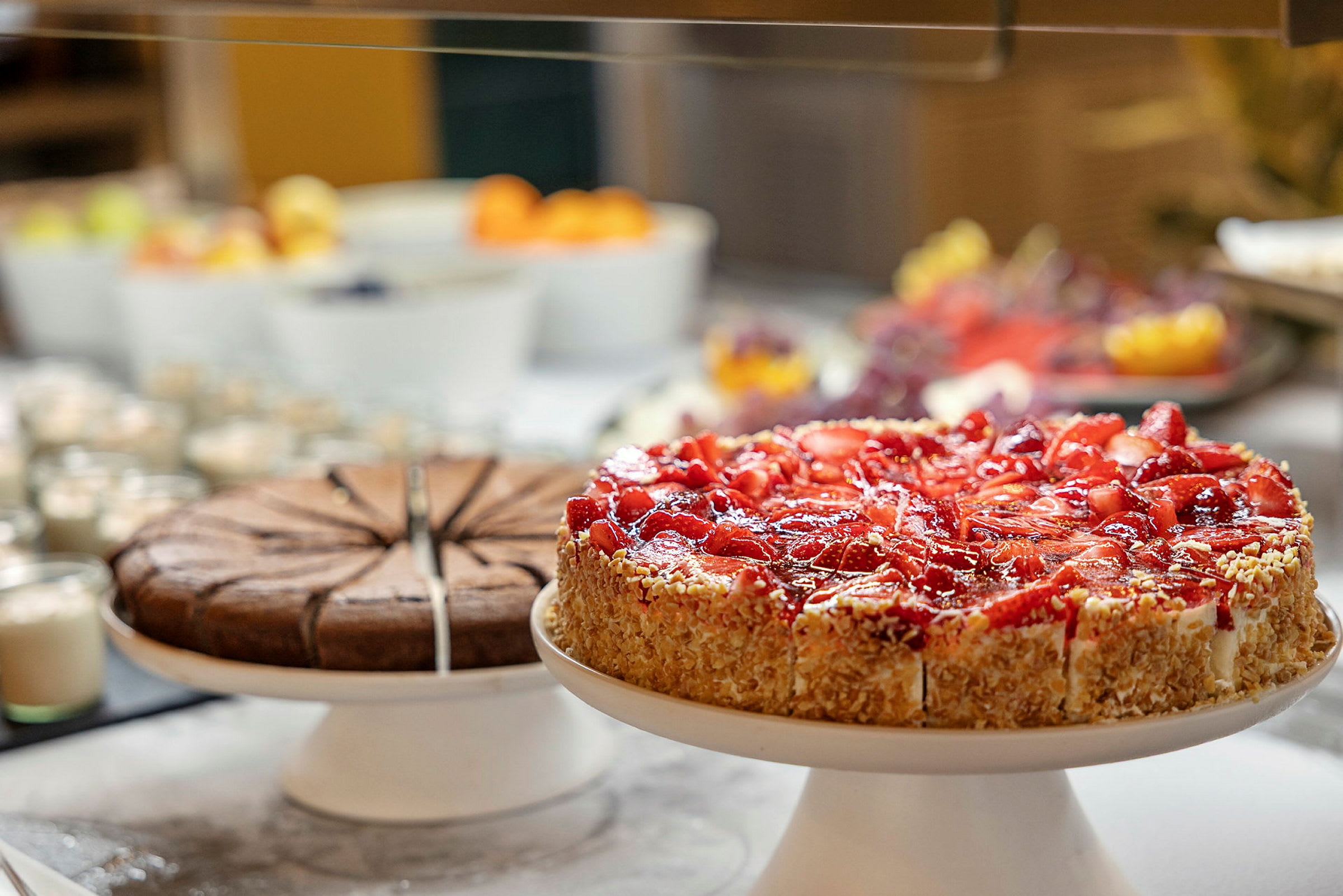 Et billede der viser to kager, en chokoladekage og en jordbærkage, på et buffetbord. (AI-genereret tekst)
