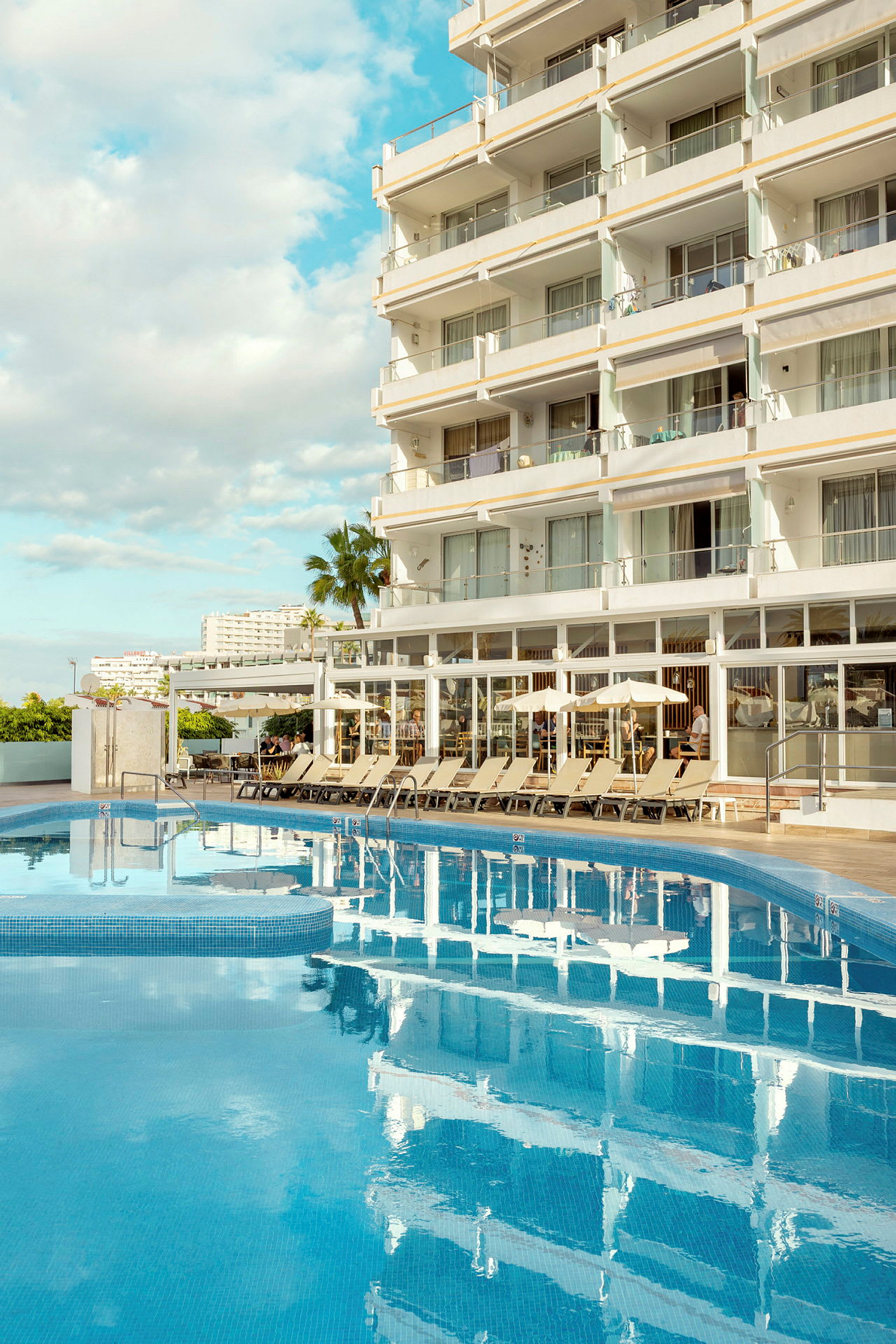 Et hotel ved en pool med liggestole omkring. (AI-genereret tekst)