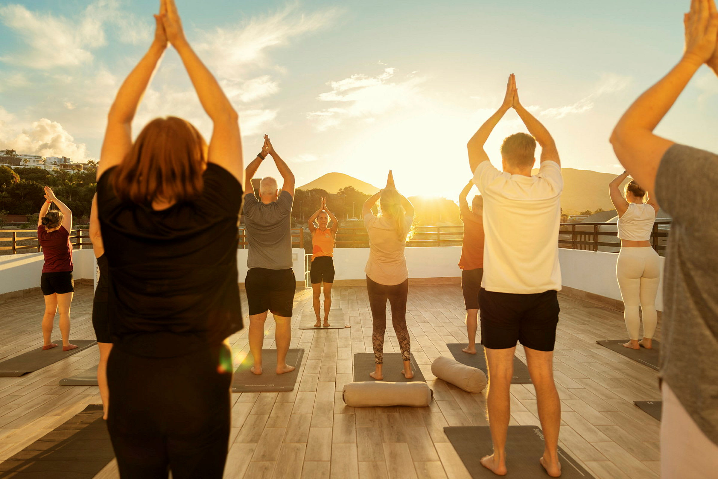 En gruppe mennesker udfører yogapositioner på en udendørsplatform ved solnedgang. (AI-genereret tekst)