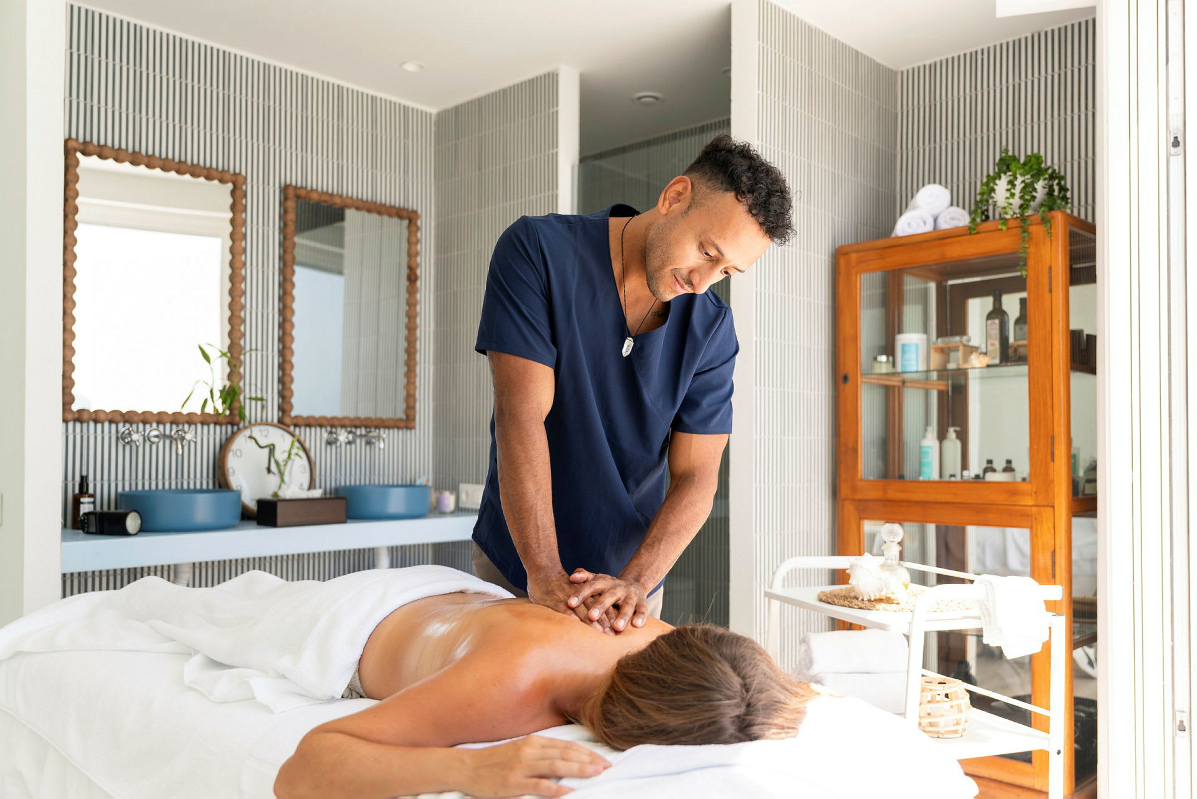 En person får en rygmassage af en massør i et lyst og velorganiseret behandlingsrum. (AI-genereret tekst)