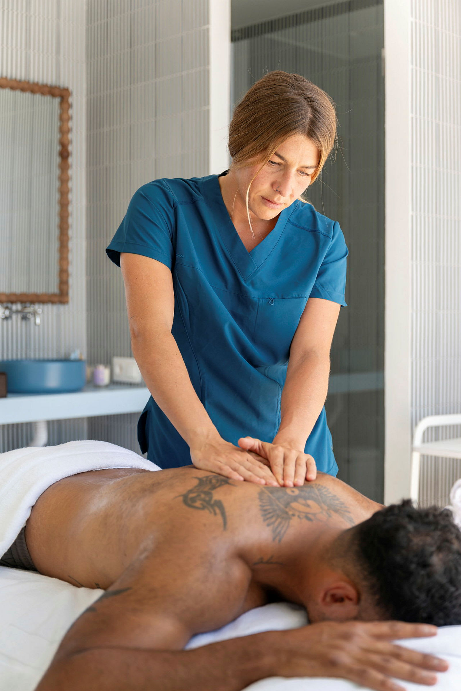 En person modtager en rygmassage af en massør iført blåt arbejdstøj. (AI-genereret tekst)