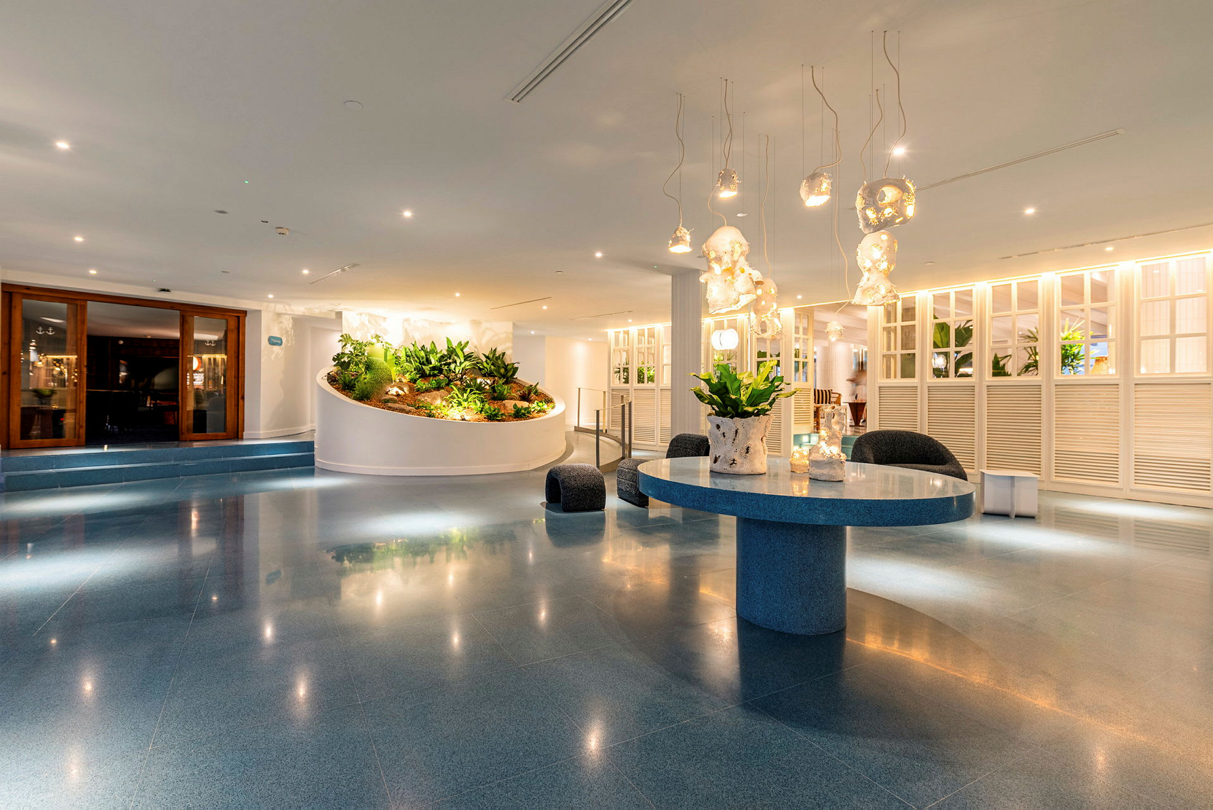 Et moderne hotelværelse med dekorative lamper, et rundt bord og grøn beplantning. (AI-genereret tekst)