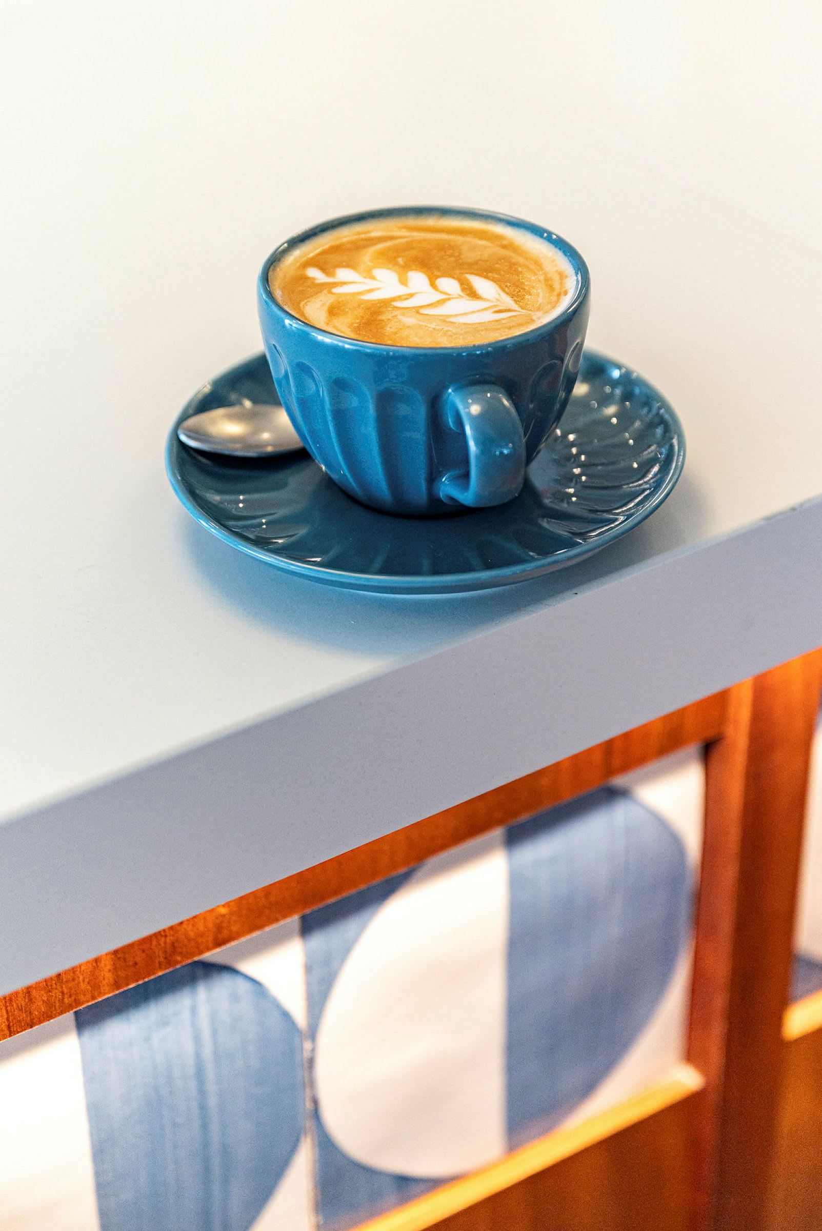 En kop kaffe med latte art på et hvidt bord. (AI-genereret tekst)