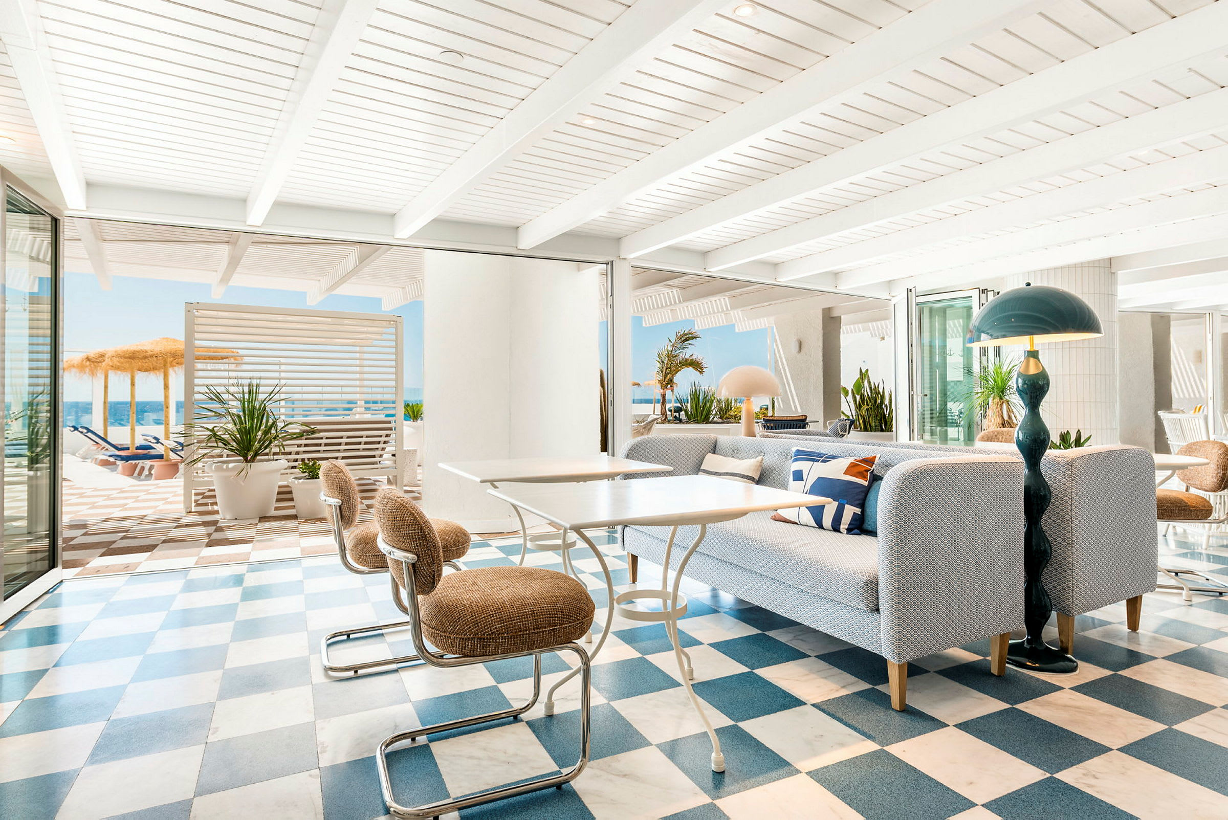 Lys og moderne lounge med ternet gulv og udsigt til en solterrasse. (AI-genereret tekst)