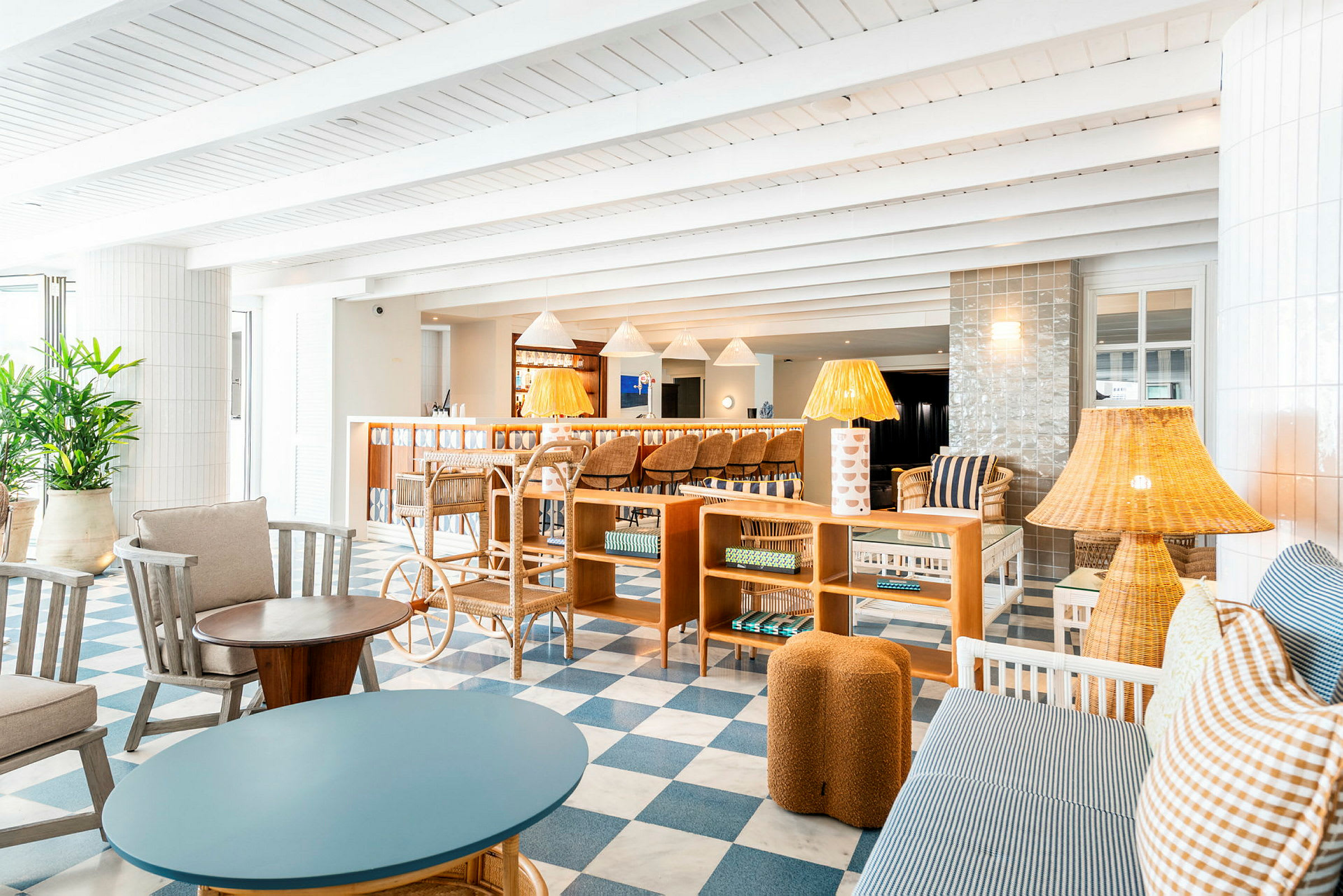 Interiør af en lys og elegant indrettet lounge med sofaer, lænestole, lamper og et ternet gulv i blåt og hvidt. (AI-genereret tekst)