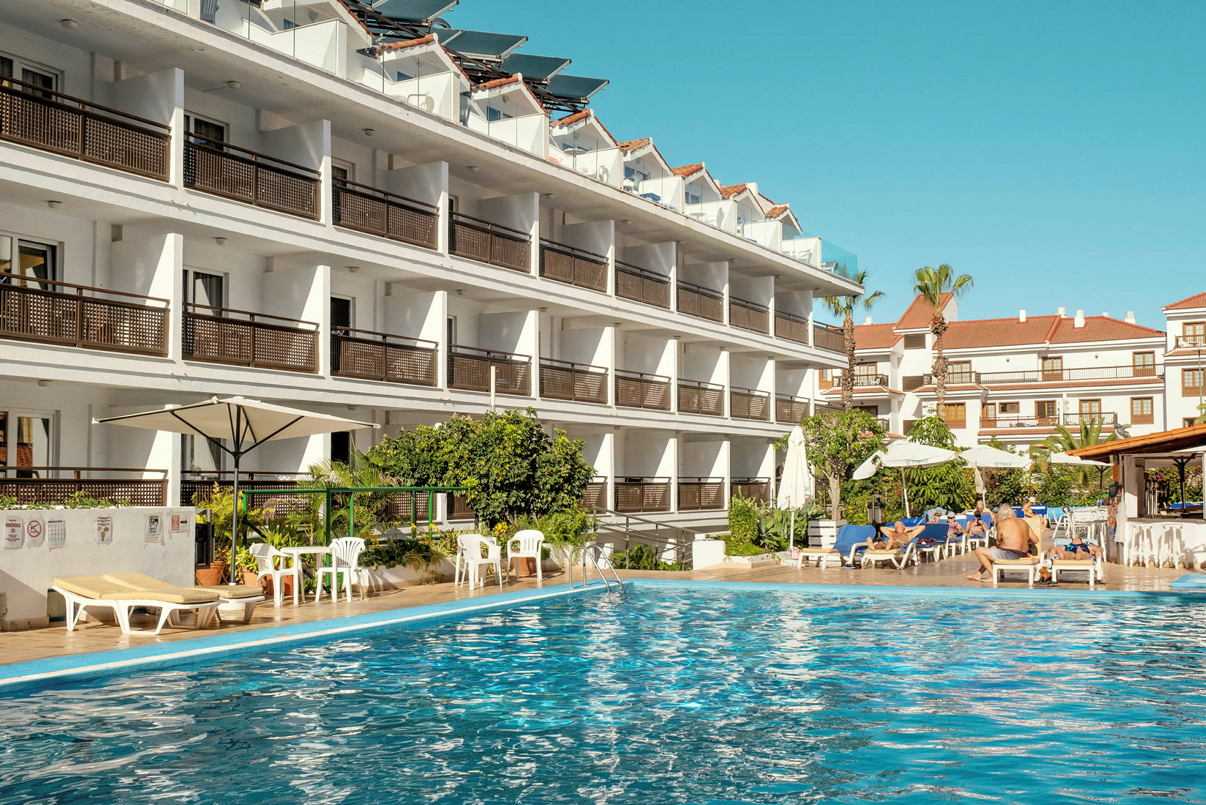 Hotelbygning ved en swimmingpool. (AI-genereret tekst)
