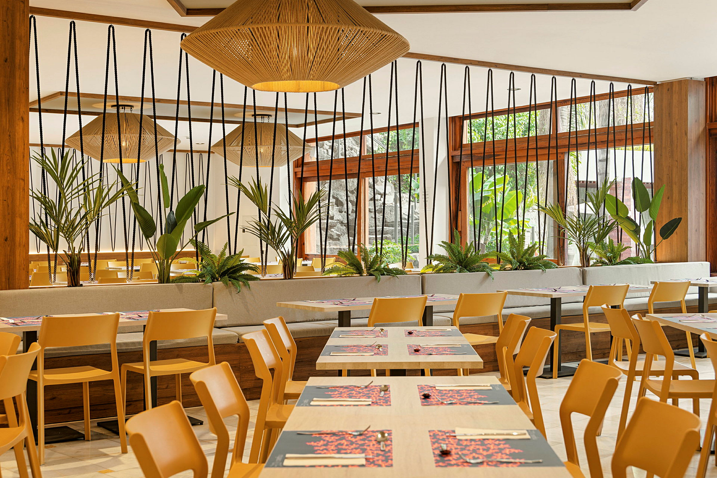 Et moderne indrettet restaurantområde med træstole, borde og grønne planter. (AI-genereret tekst)