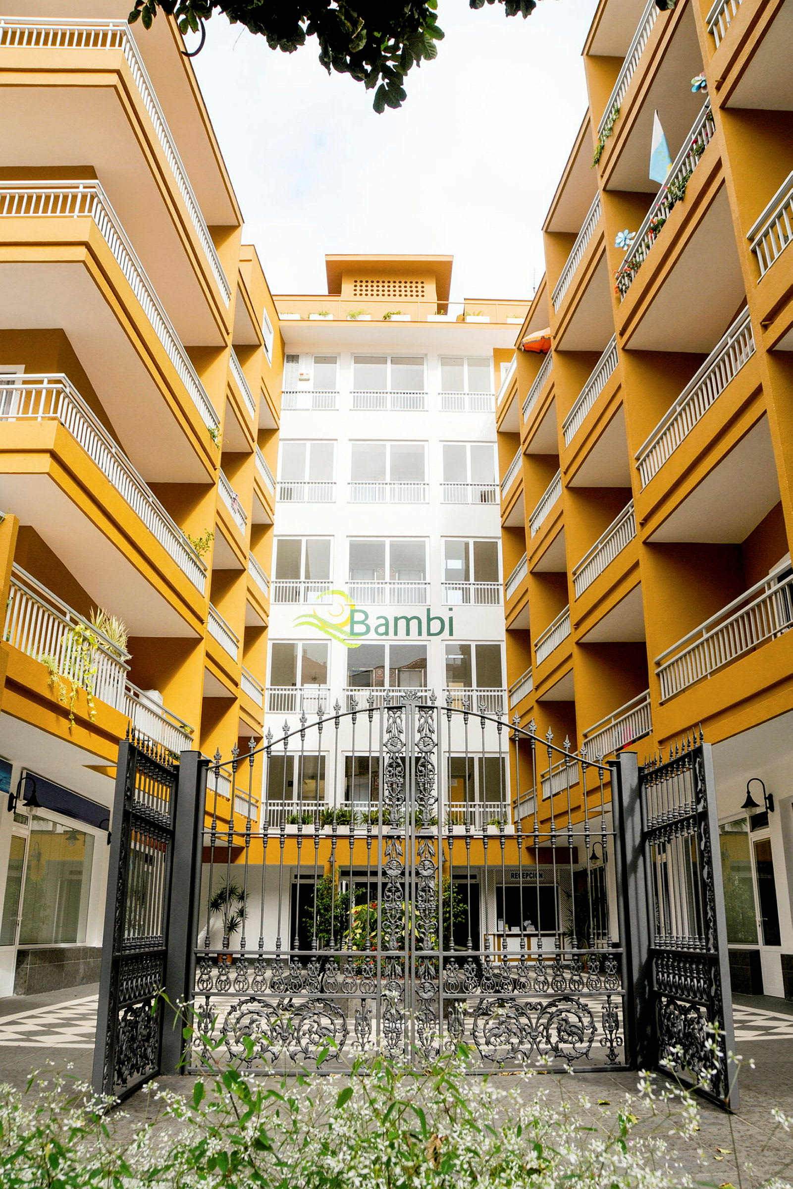 Indgang til hotelkompleks med flere etager og altaner. (AI-genereret tekst)