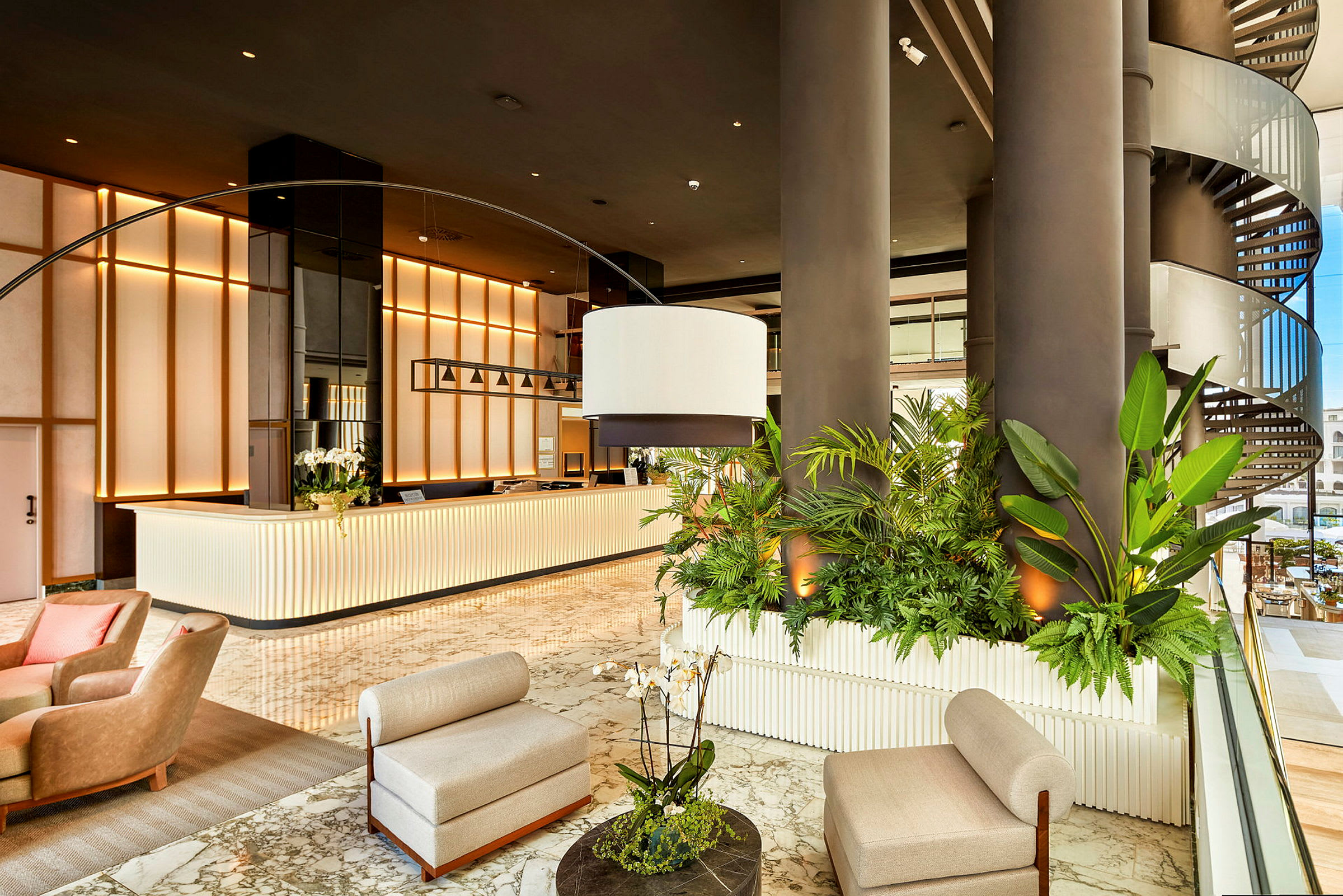 Lys hotellets lobby med reception, grønne planter og siddemøbler. (AI-genereret tekst)