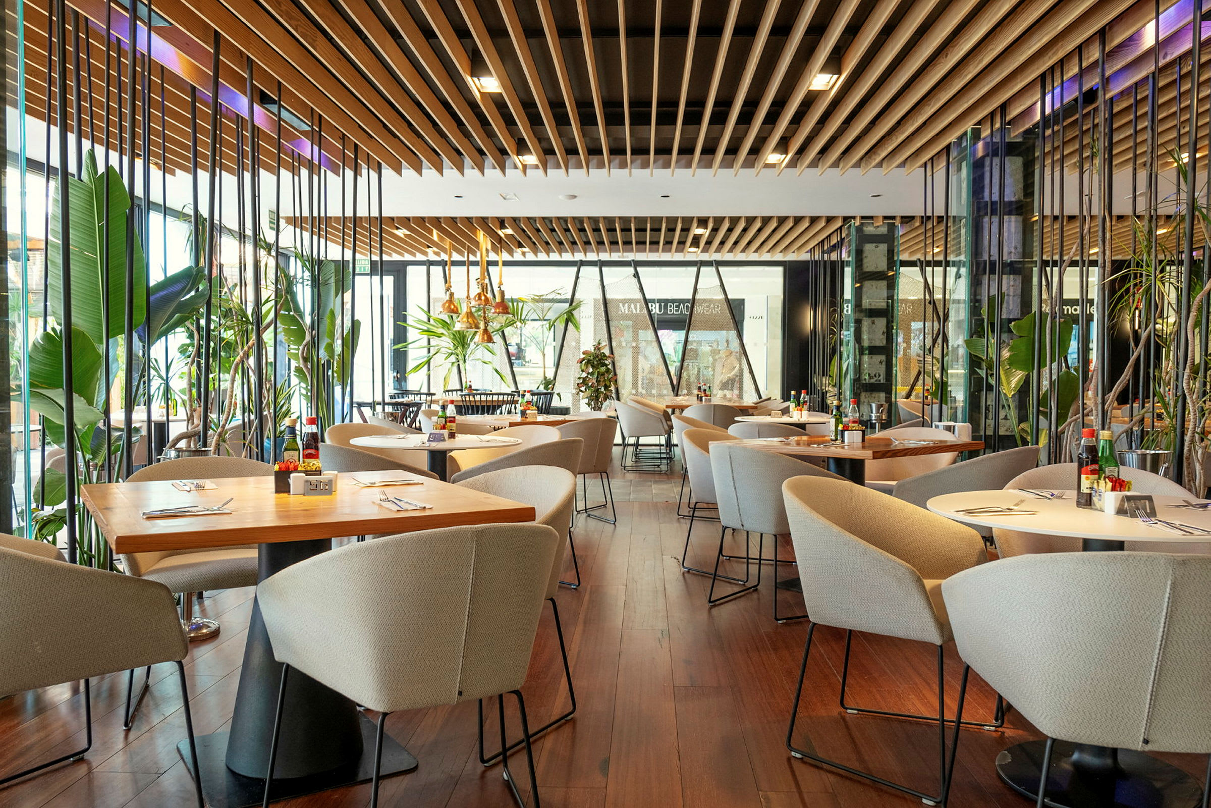 Moderne restaurant med borde, stole og frodige planter. (AI-genereret tekst)