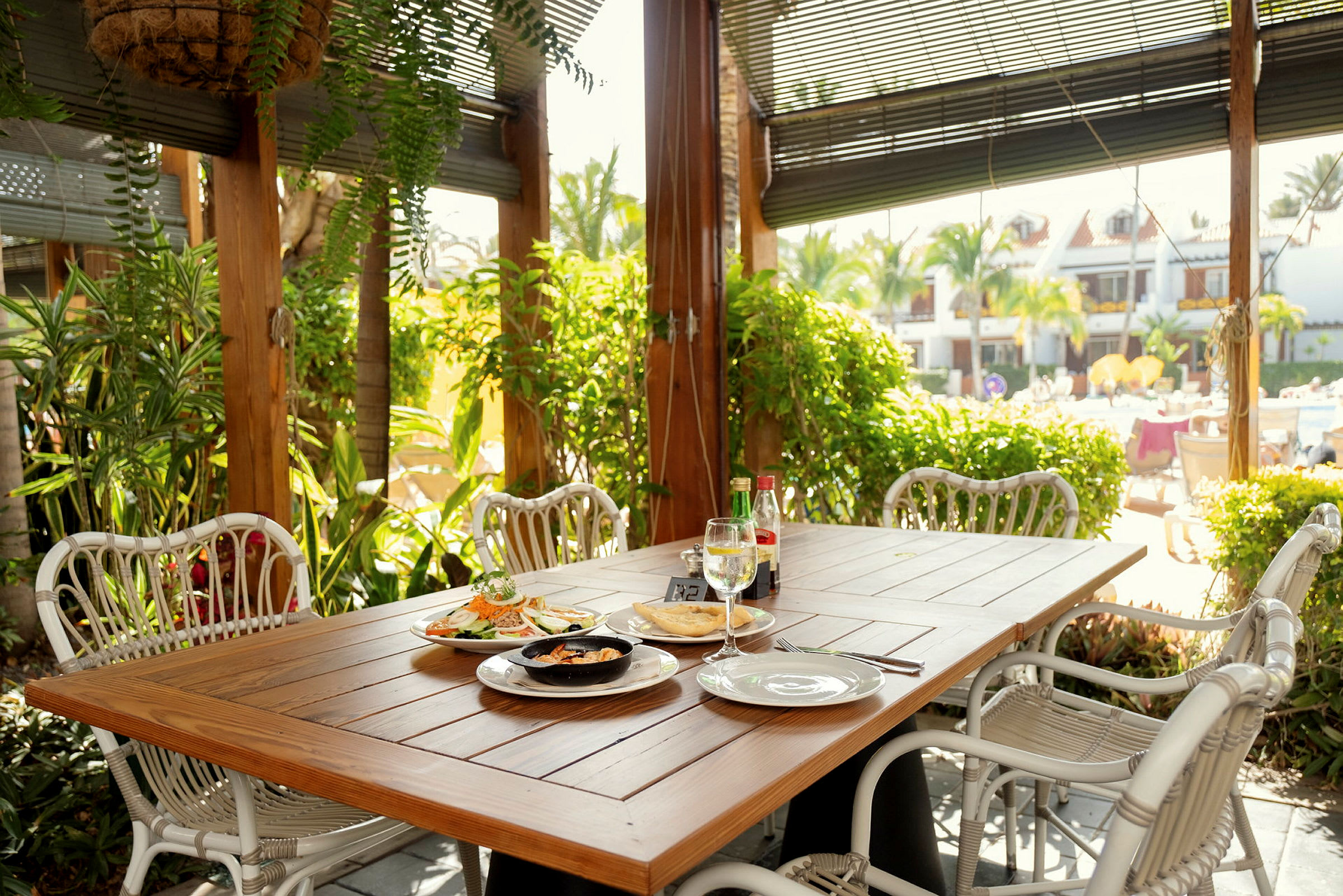 Et bord med mad placeret på en terrasse omgivet af grønne områder. (AI-genereret tekst)