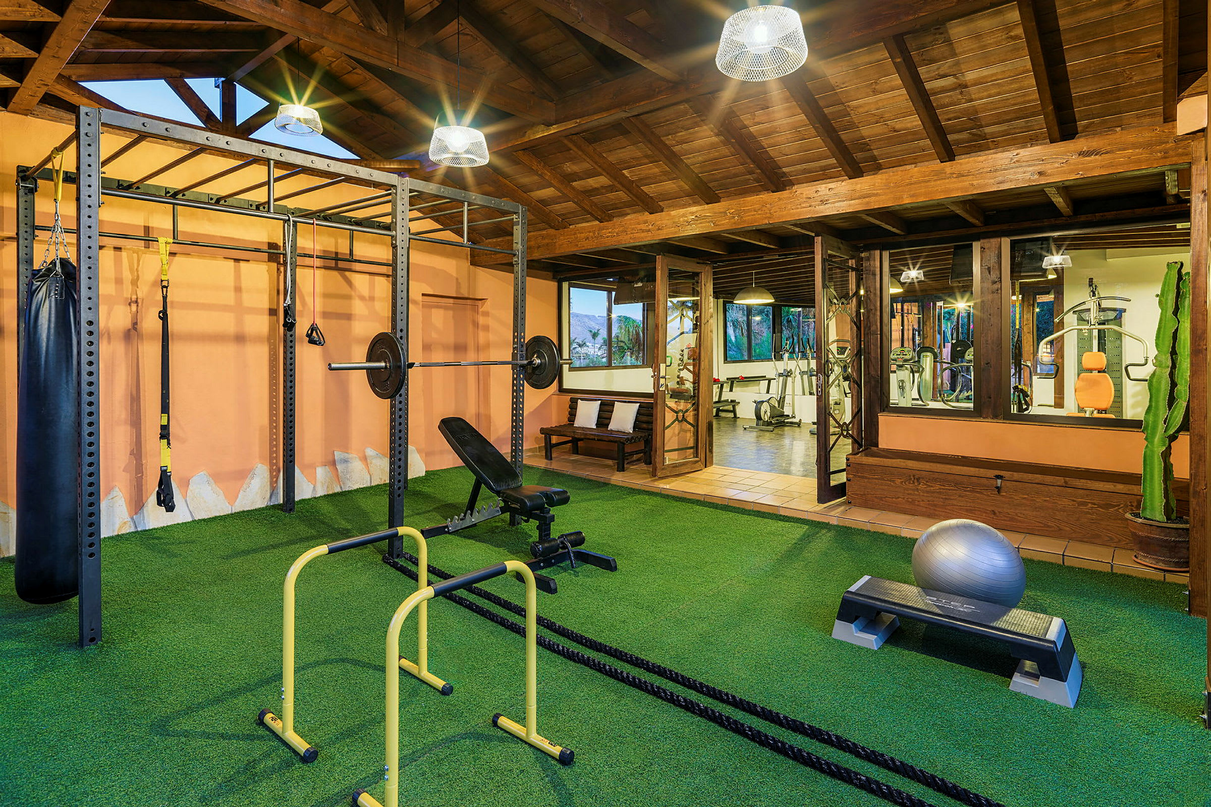 Et fitnesscenter med træningsudstyr såsom vægtstang, ribbevæg og en stepbænk på en kunstgræsmåtte. (AI-genereret tekst)
