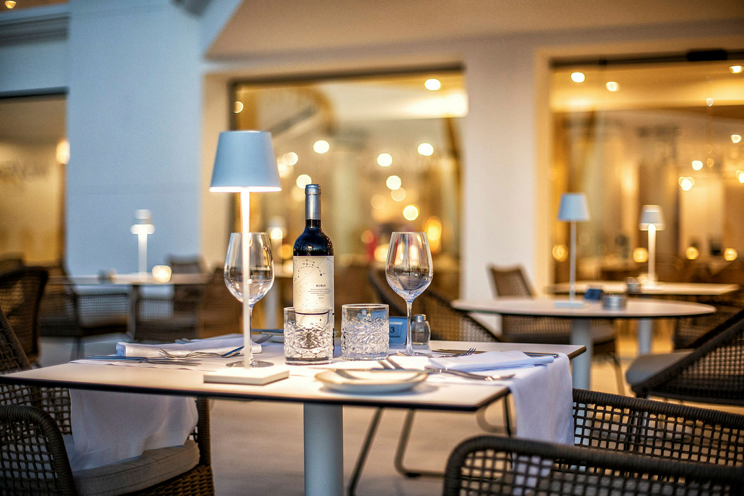 Et dækket bord med en flaske vin og glas på en restaurant. (AI-genereret tekst)