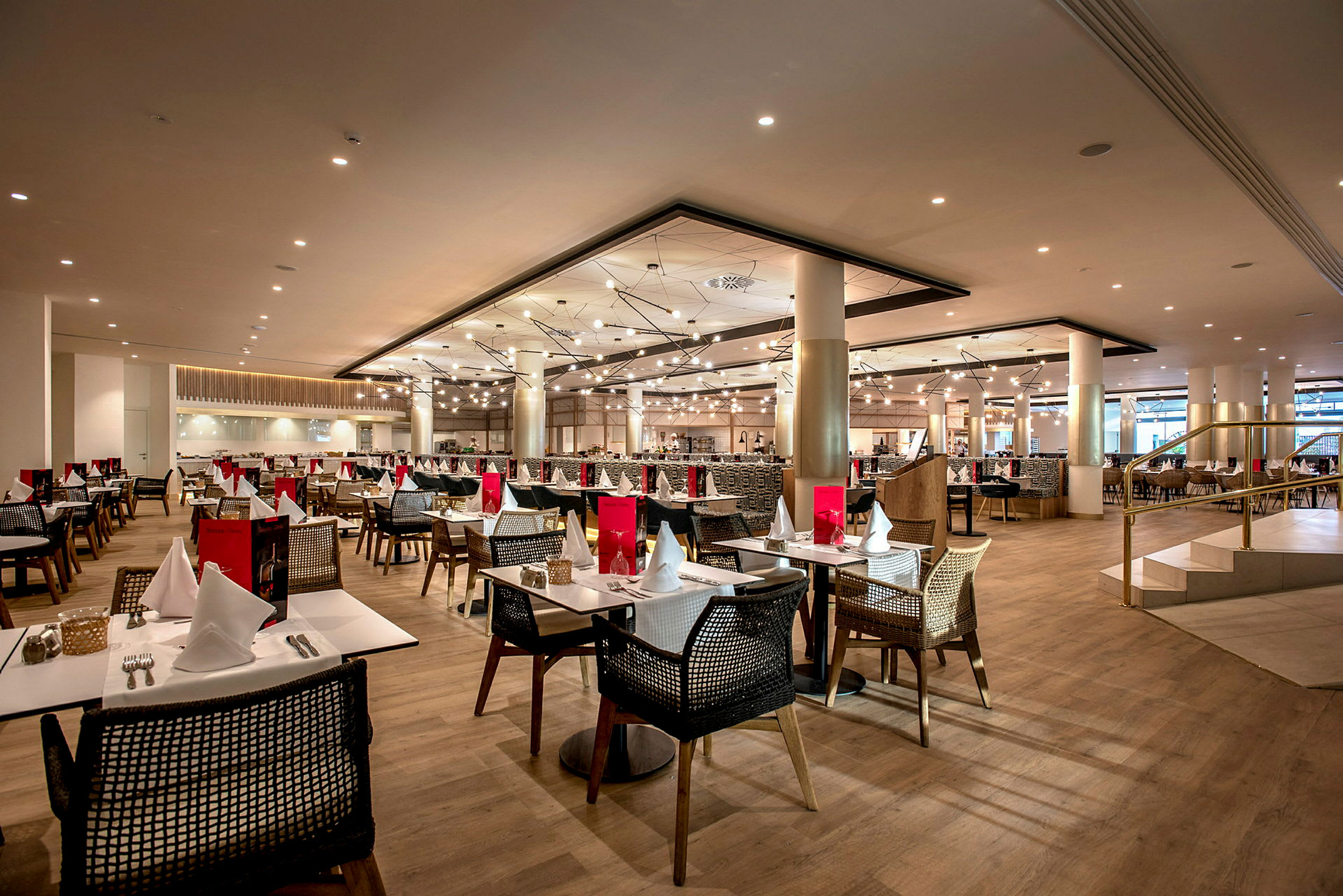 Billede af en restaurant med flere opdækkede borde og stole i et moderne indendørs miljø. (AI-genereret tekst)