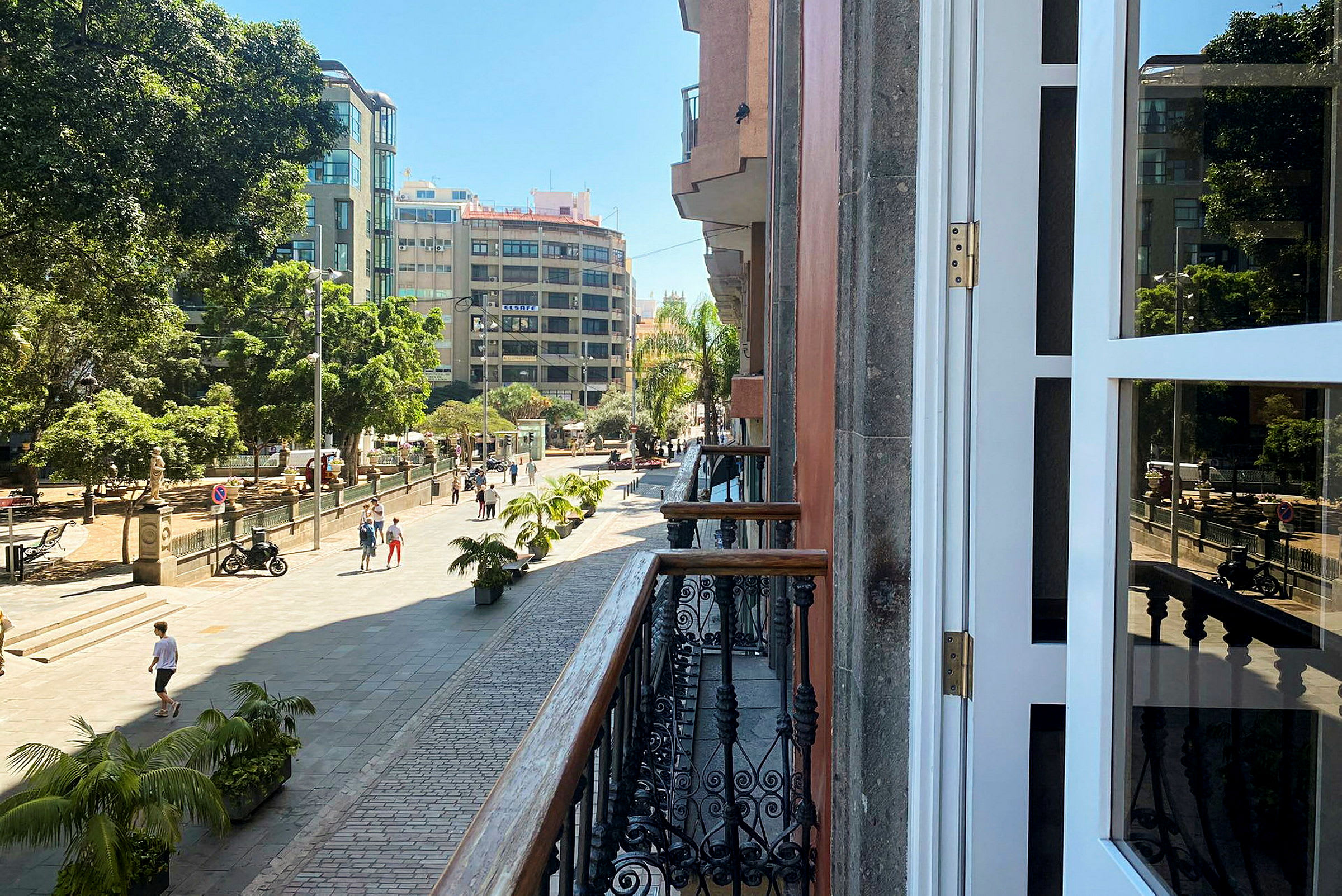 Udsigt fra en balkon til en bygade med gangområde og grønne områder. (AI-genereret tekst)