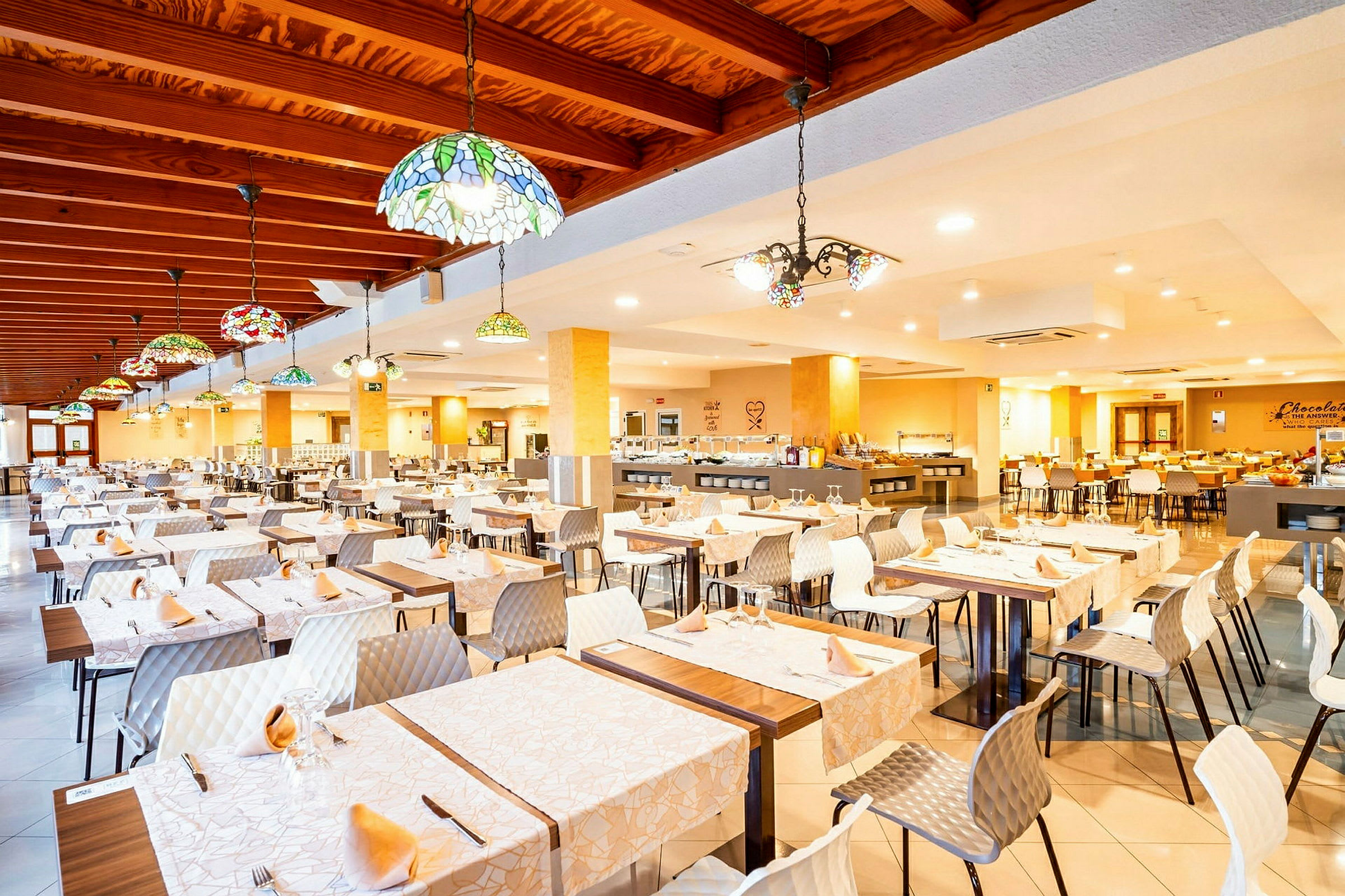 En rummelig restaurant med dækkede borde og farverige loftslamper. (AI-genereret tekst)