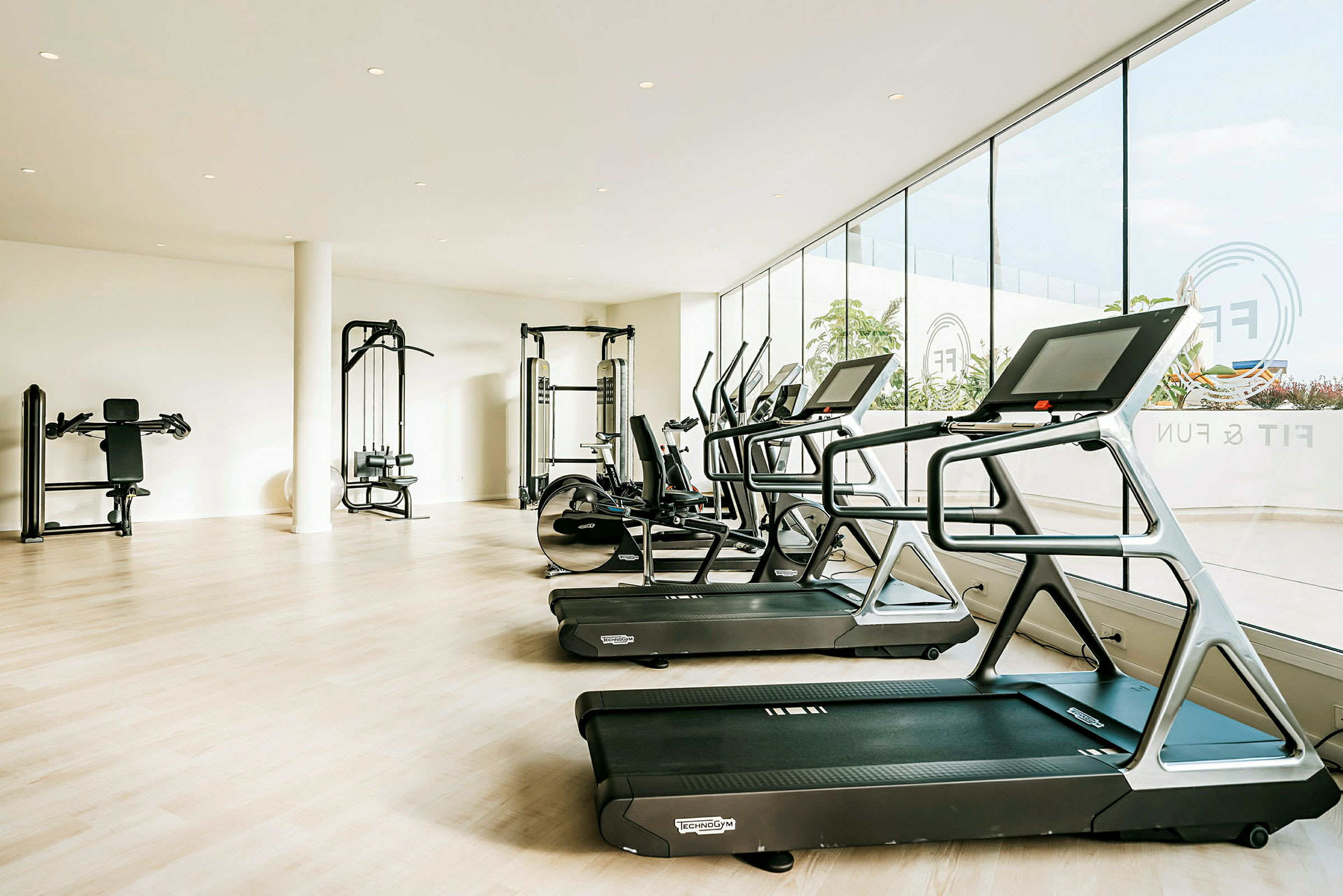 Et lyst træningscenter med fitnessudstyr som løbebånd og maskiner. (AI-genereret tekst)