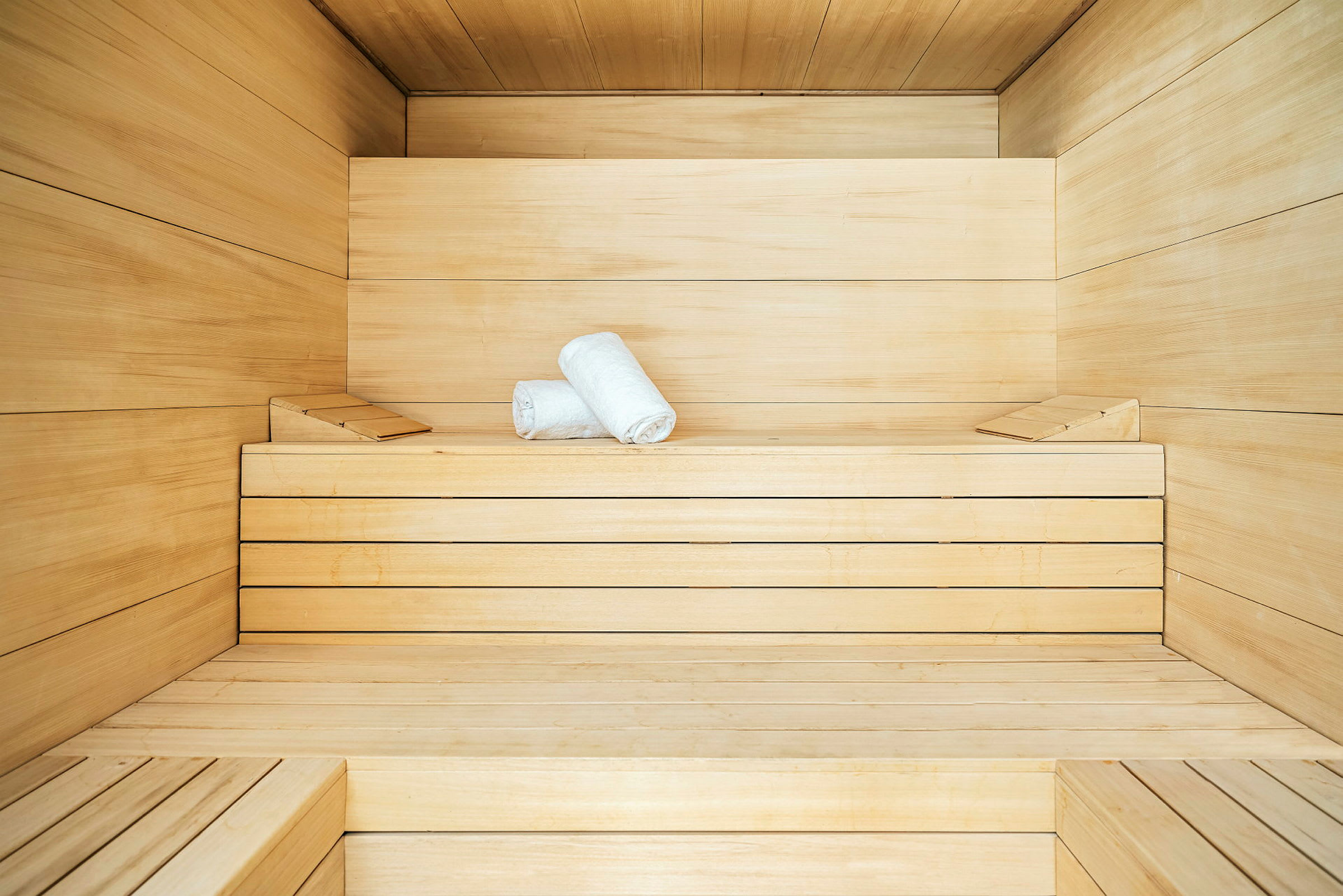 Interiør af en sauna med to sammenrullede håndklæder på en træbænk. (AI-genereret tekst)
