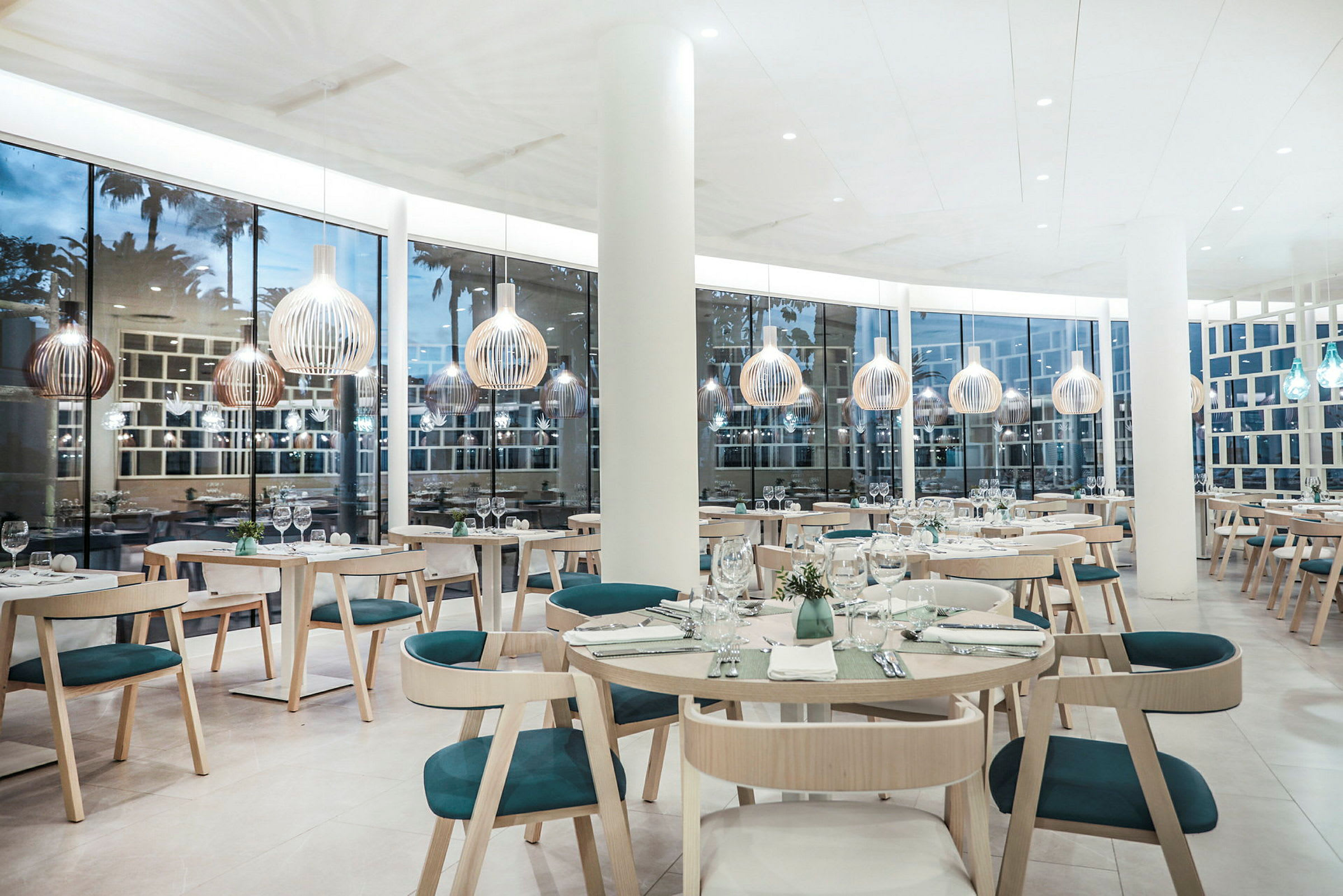 Lyse og moderne restaurantlokaler med store vinduer og stilfulde borde og stole. (AI-genereret tekst)