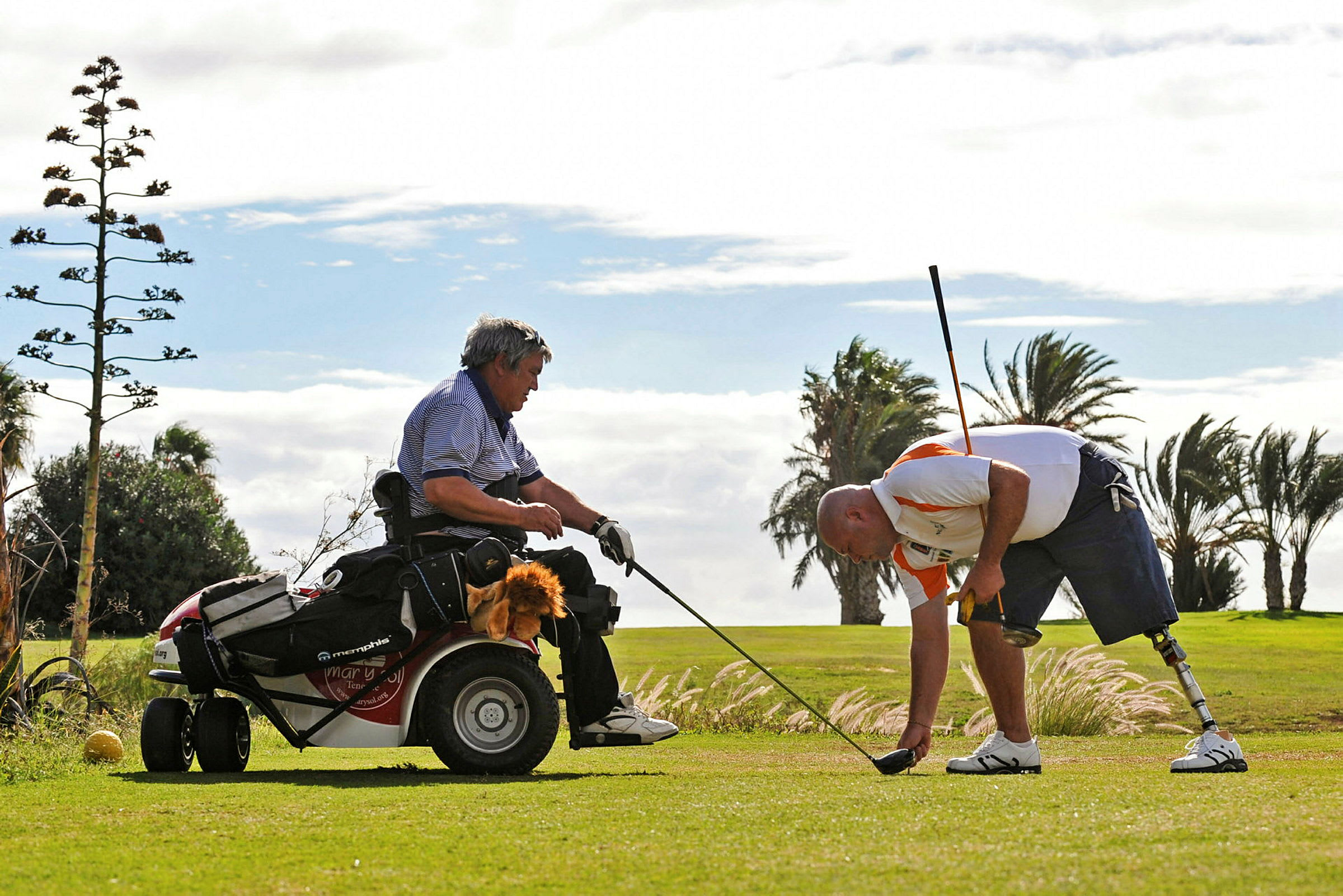 To personer spiller golf, den ene sidder i en golfvogn, og den anden bøjer sig ned på græsset med en golfkølle. (AI-genereret tekst)