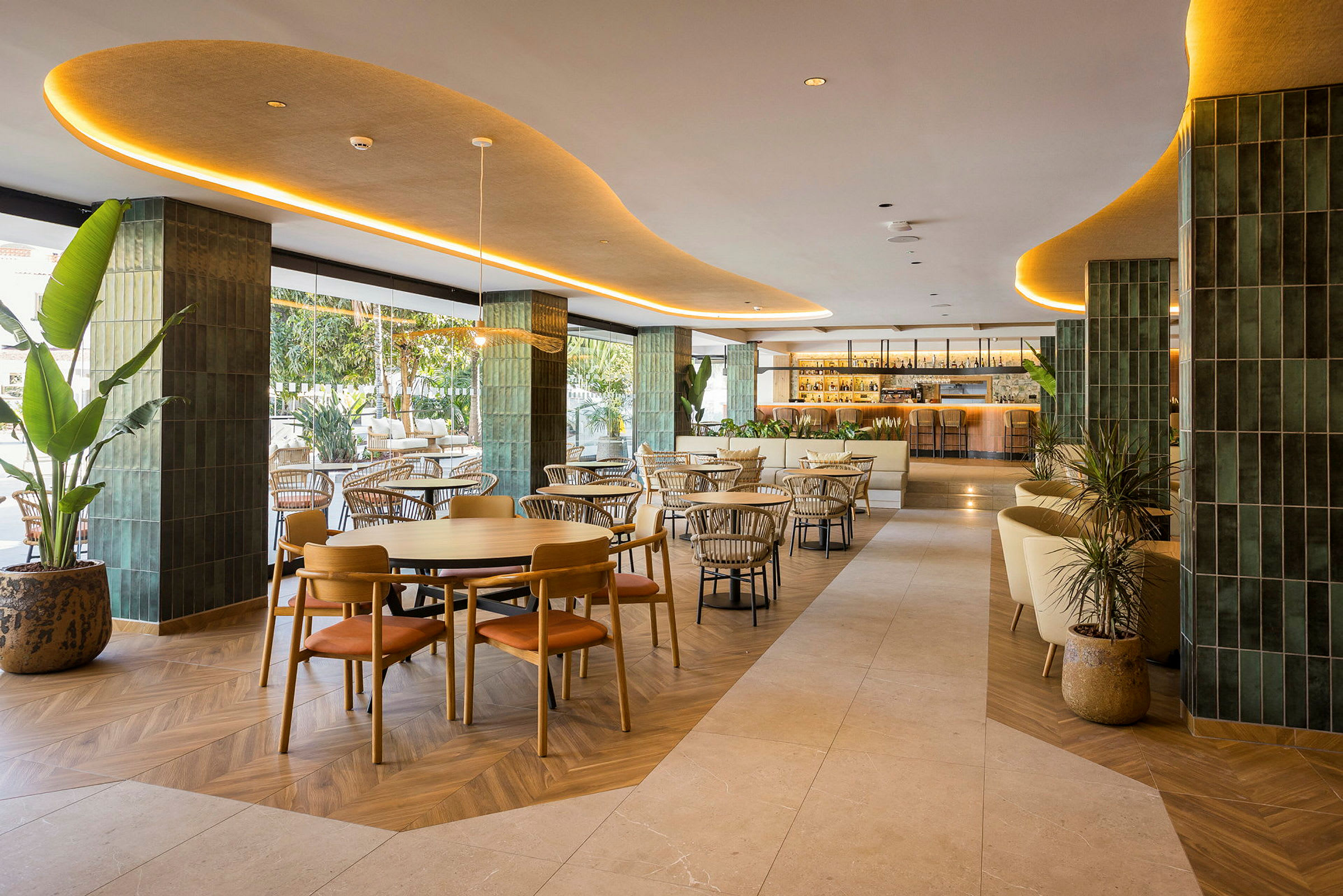 En elegant restaurant med moderne møbler og indretning, beliggende indendørs med grønne detaljer og stor bar i baggrunden. (AI-genereret tekst)