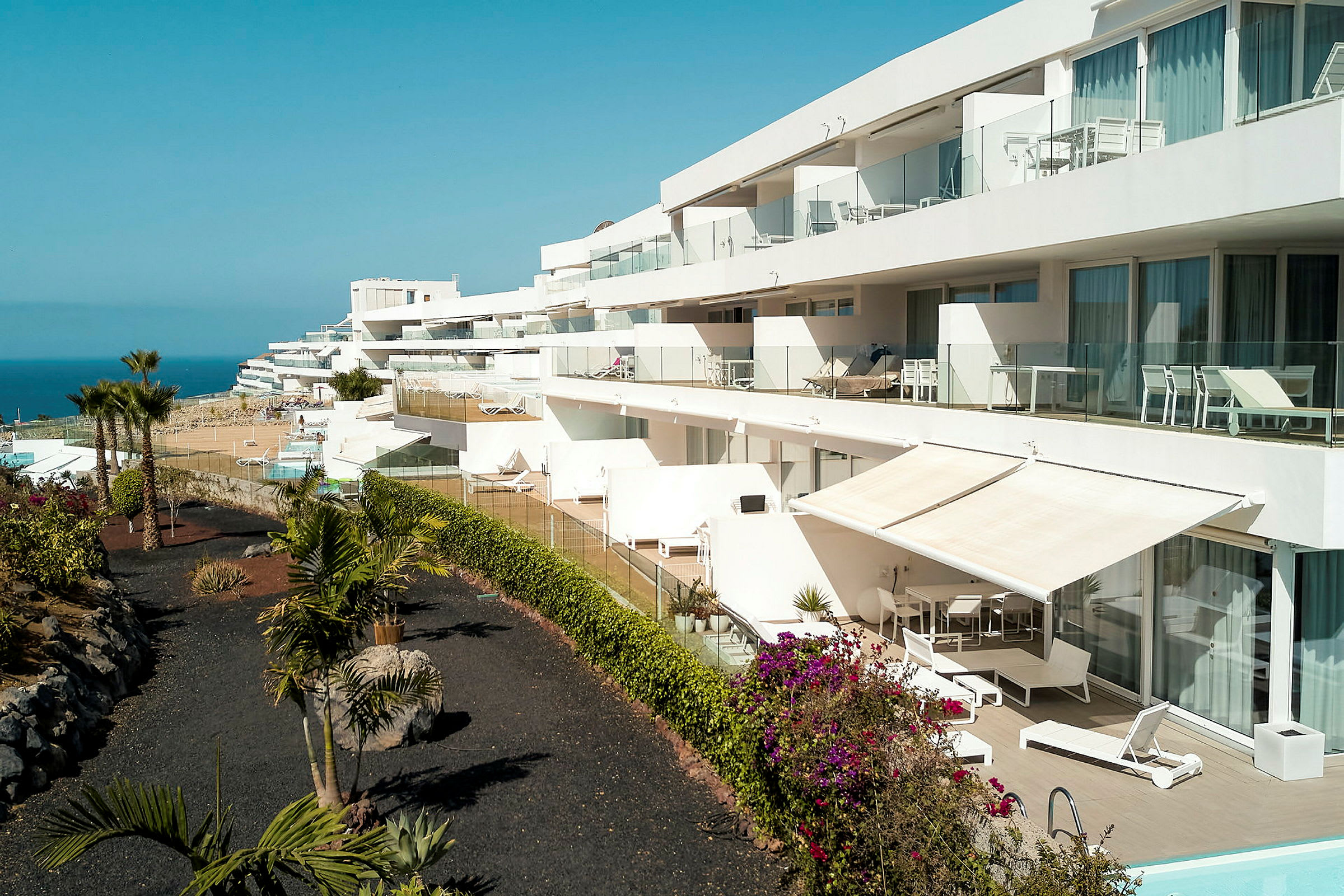 Billede af et moderne feriested med terrasselejligheder, swimmingpool og udsigt over havet. (AI-genereret tekst)
