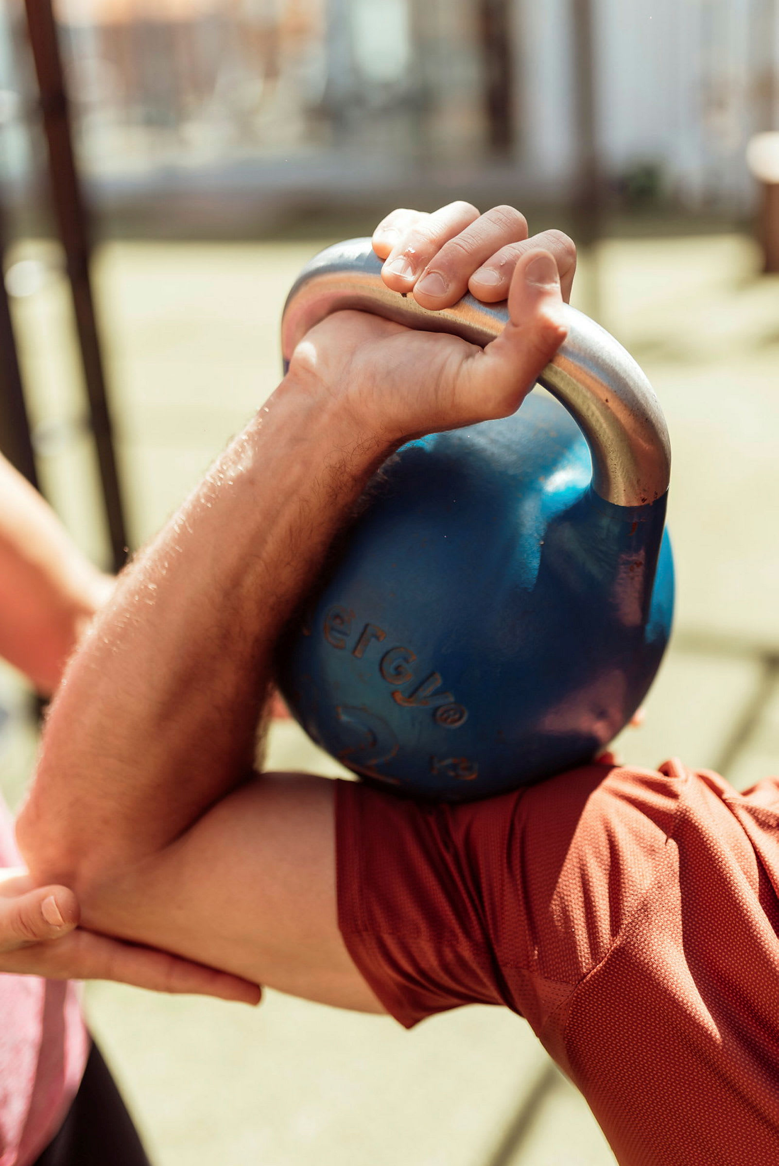 En arm holder en blå kettlebell under træning. (AI-genereret tekst)