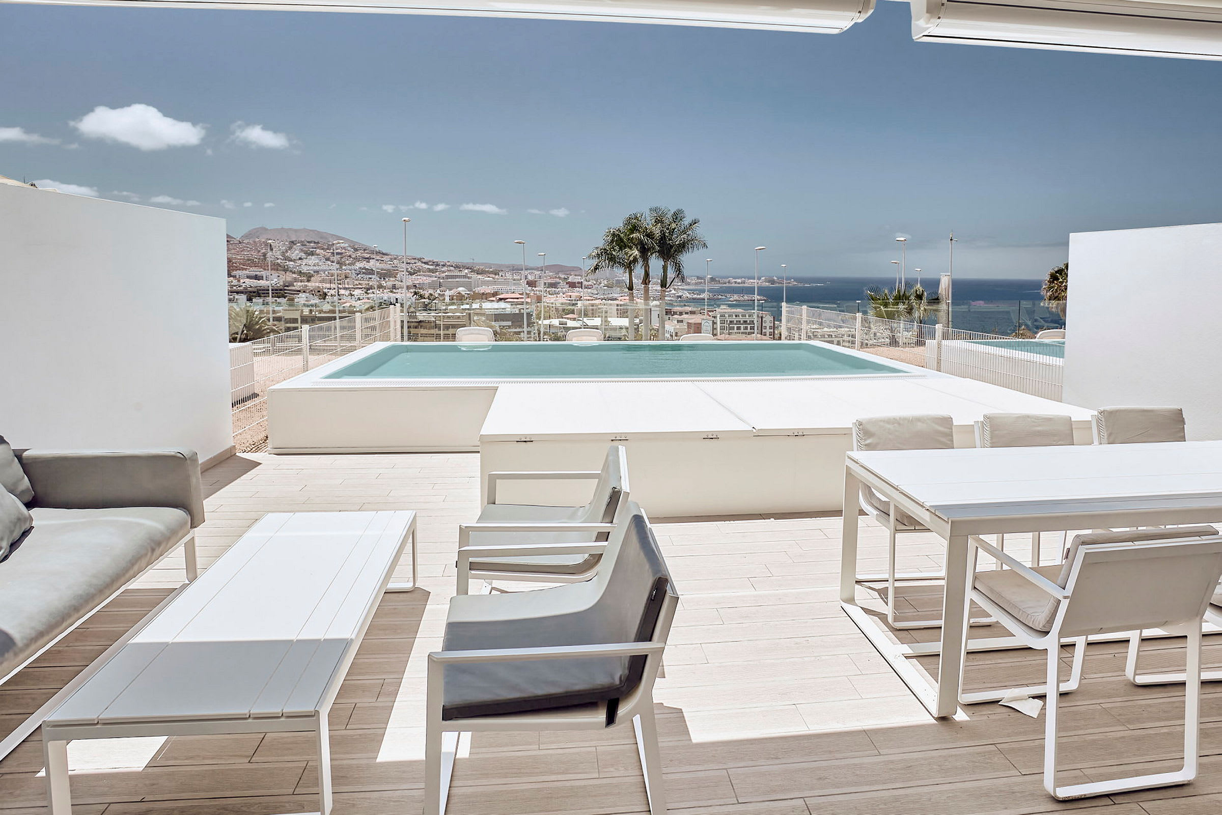 Terrasse med møbler, udsigt over poolen og havet i baggrunden. (AI-genereret tekst)