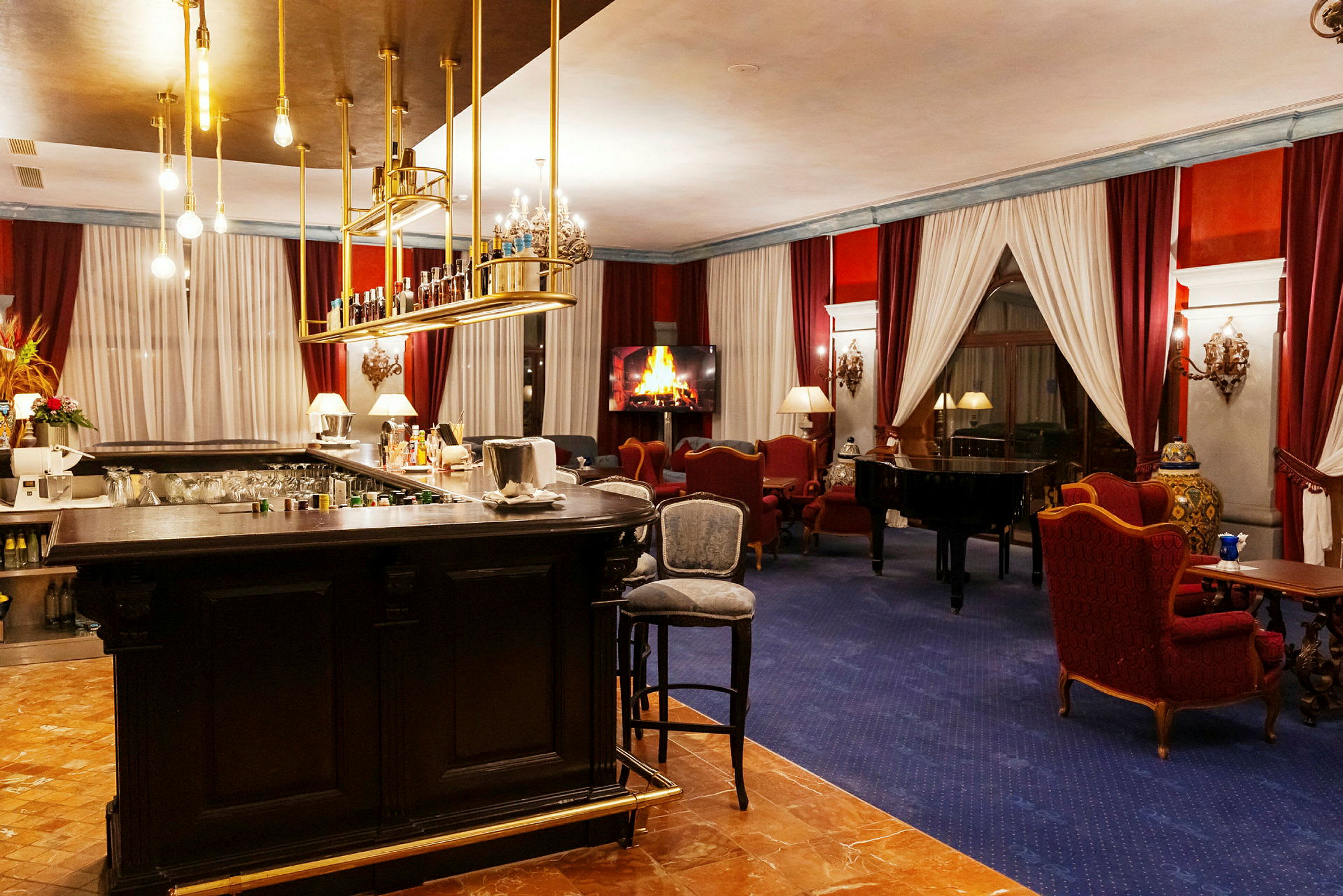 En elegant hotellounge med en bardisk, et klaver og siddeområder foran en digital ildsted. (AI-genereret tekst)