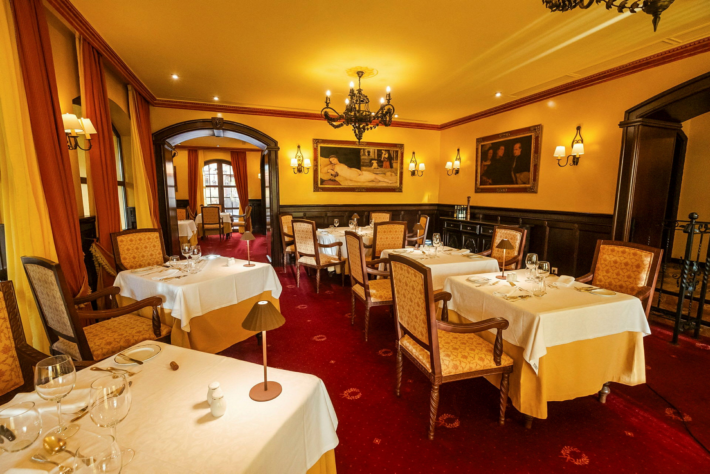 En elegant restaurant med dækkede borde, blød belysning og kunstværker på væggene. (AI-genereret tekst)