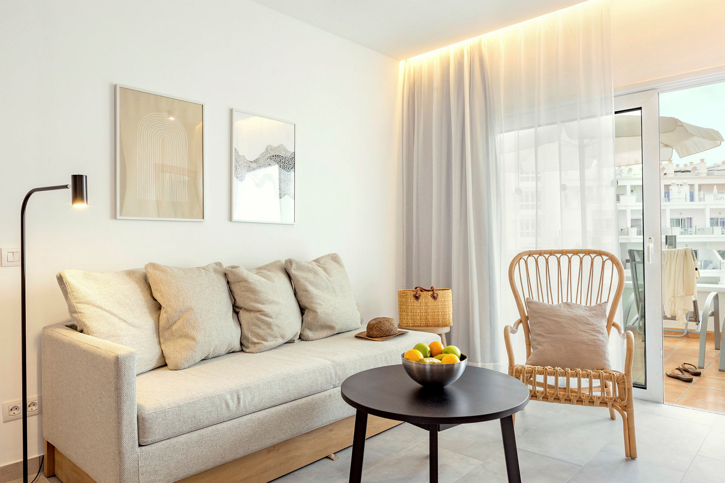 Moderne indrettet stue med sofa, lænestol og bord foran en altan. (AI-genereret tekst)