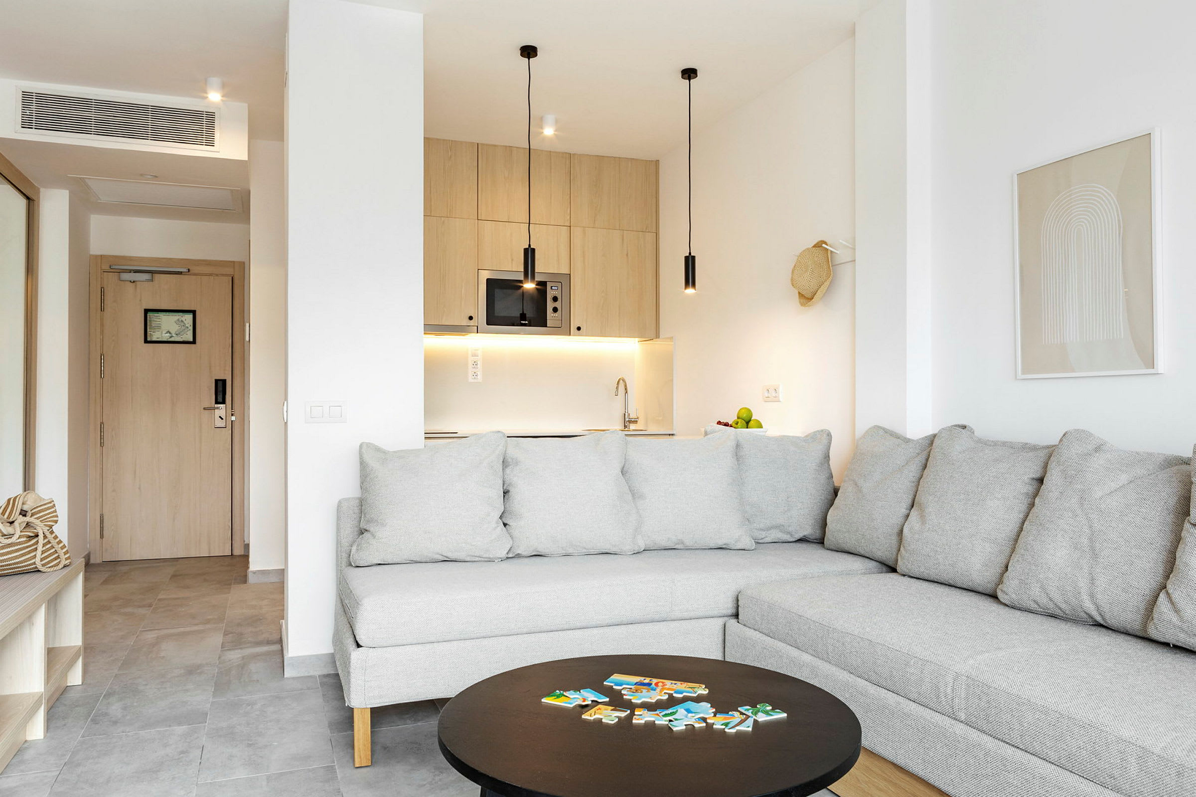 En moderne lejlighed med grå sofa og et åbent køkkenområde. (AI-genereret tekst)