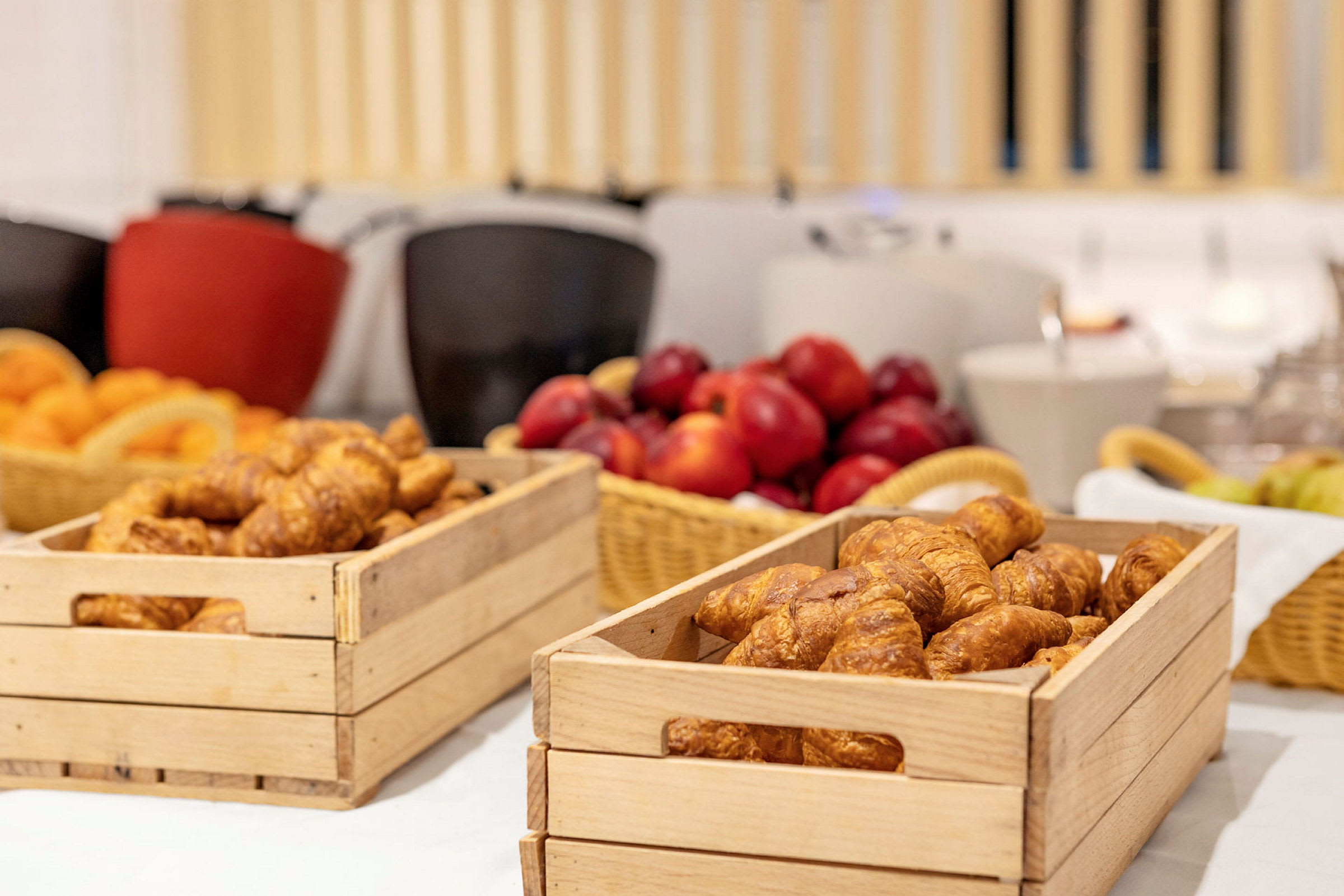 Trækasser med croissanter og frugt på et bord. (AI-genereret tekst)