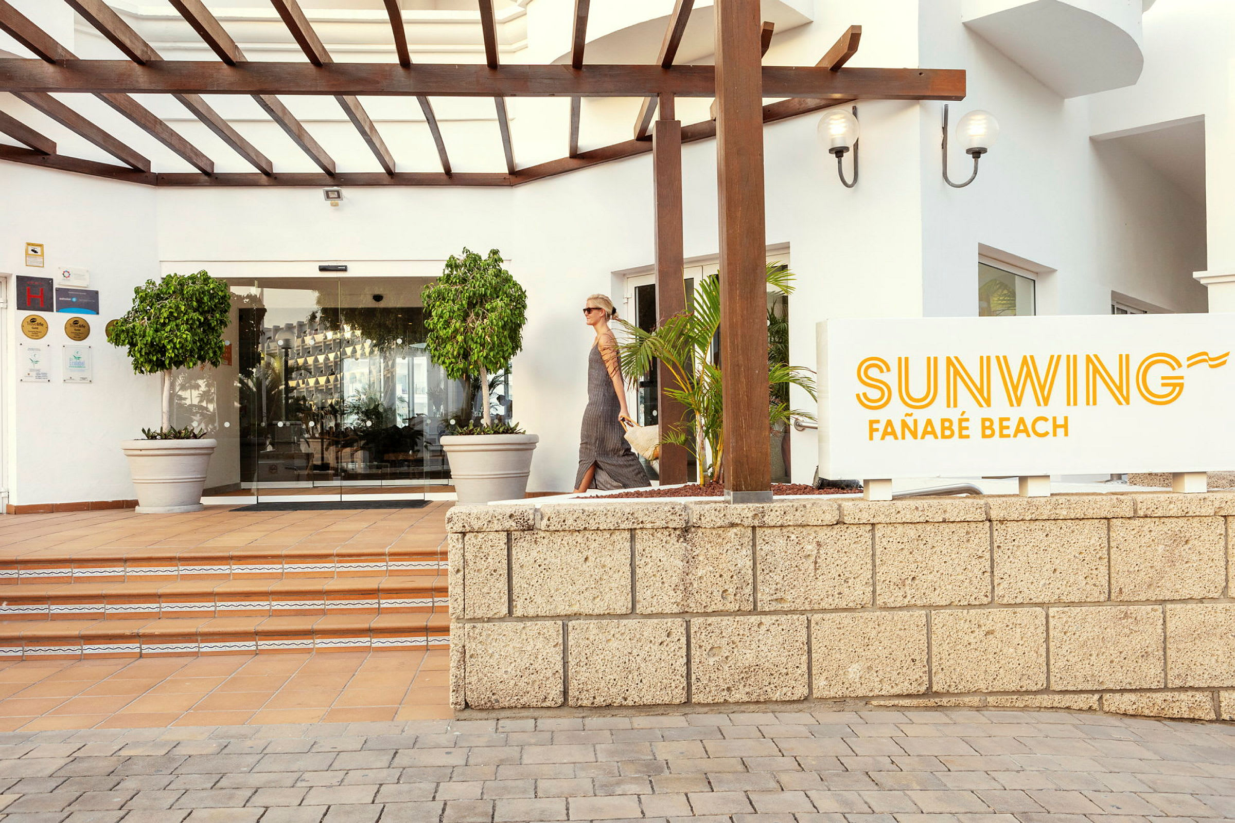 Indgangen til Sunwing Fañabé Beach med skilt og glasdøre. (AI-genereret tekst)