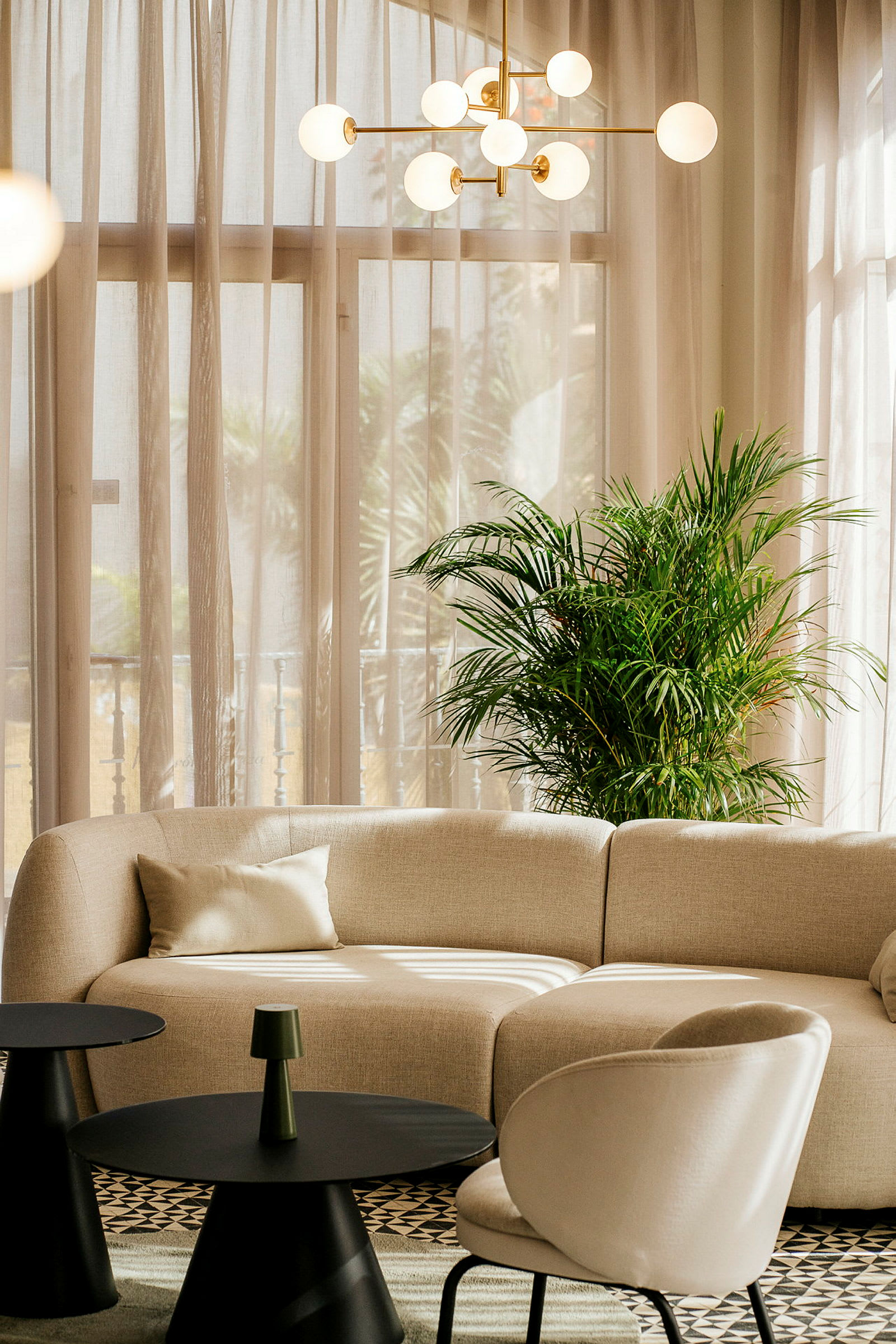 En sofagruppe med beige sofa, grøn plante og runde borde. (AI-genereret tekst)