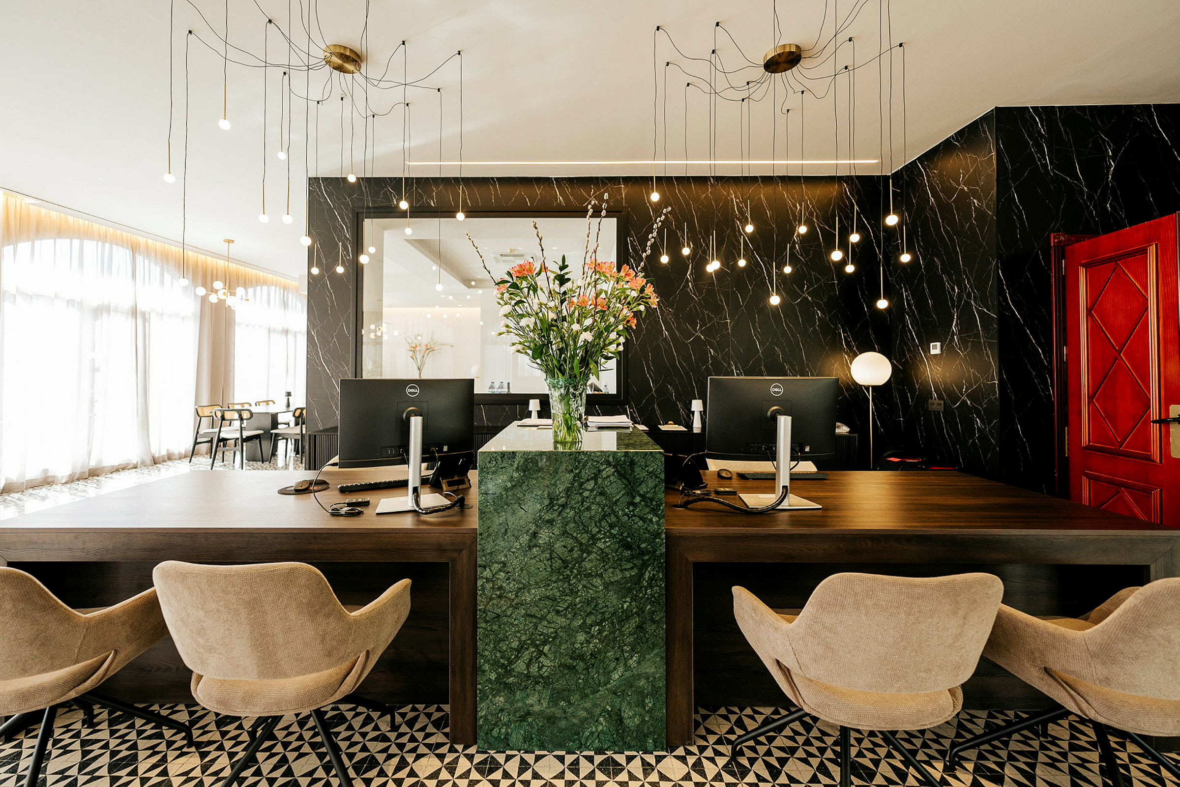 Reception med to skriveborde, kontorstole og en grøn marmorsøjle med blomster. (AI-genereret tekst)