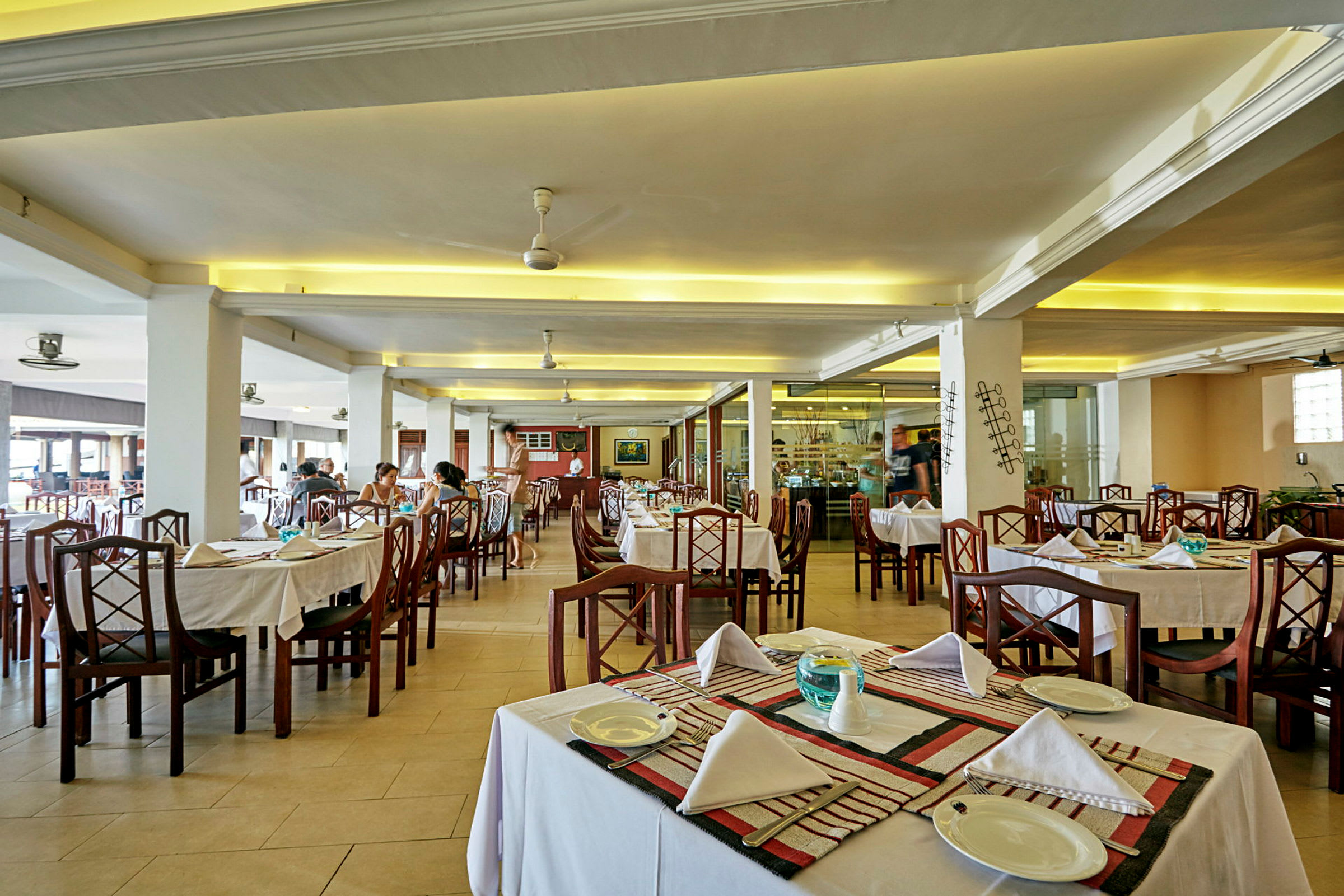 Interiør af en restaurant med opdækkede borde og stole. (AI-genereret tekst)