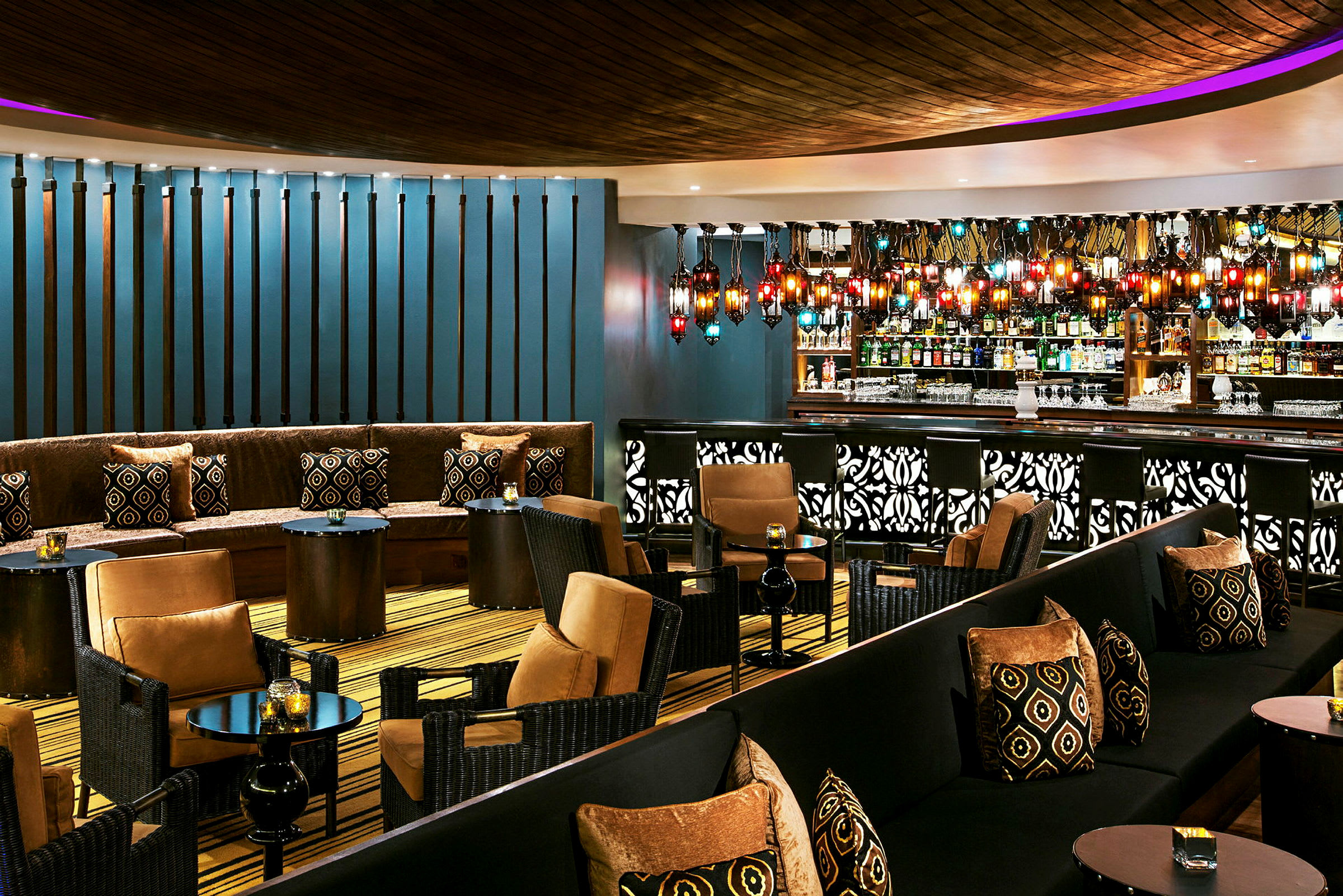 En stilfuld lounge med siddepladser, små borde og en bar. Farverigt lys og detaljer pryder indretningen. (AI-genereret tekst)