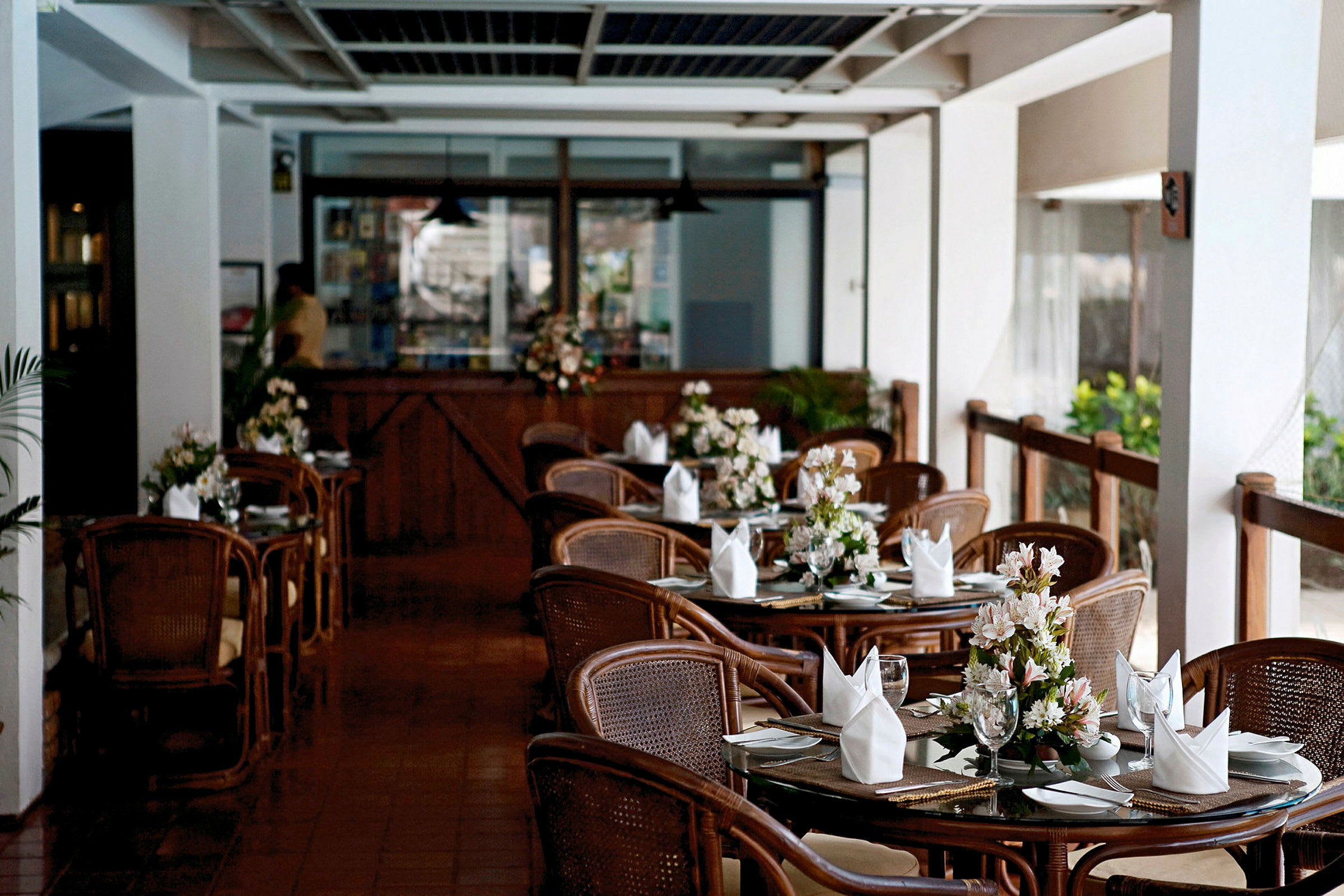 En restaurant med dækkede borde og blomster på hver bord. (AI-genereret tekst)