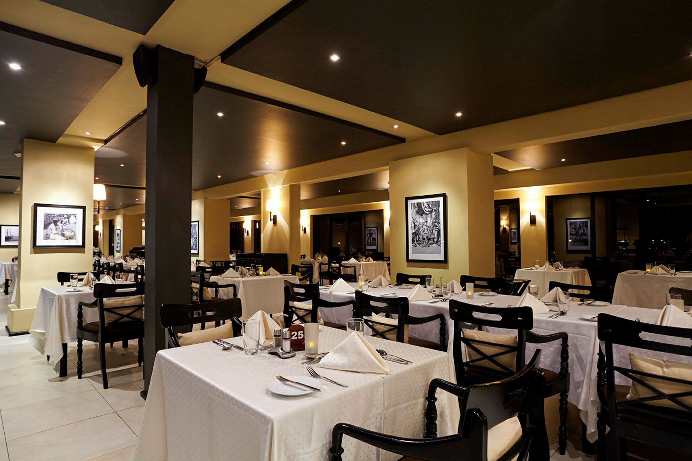 Interiør af en elegant restaurant med dækkede borde og indrammet kunst på væggene. (AI-genereret tekst)