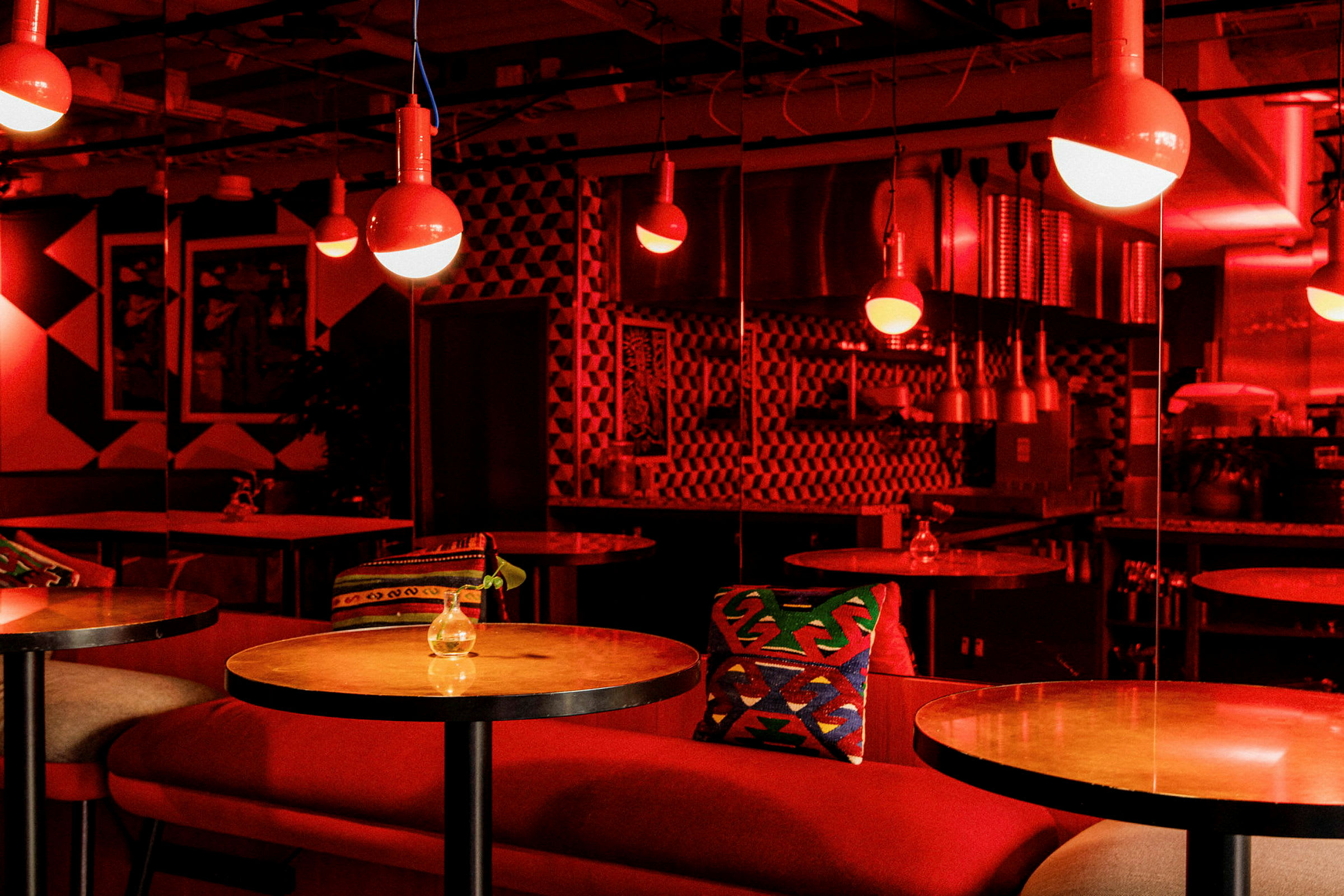 Indretning af en moderne restaurant med røde bordlamper og farverige puder. (AI-genereret tekst)