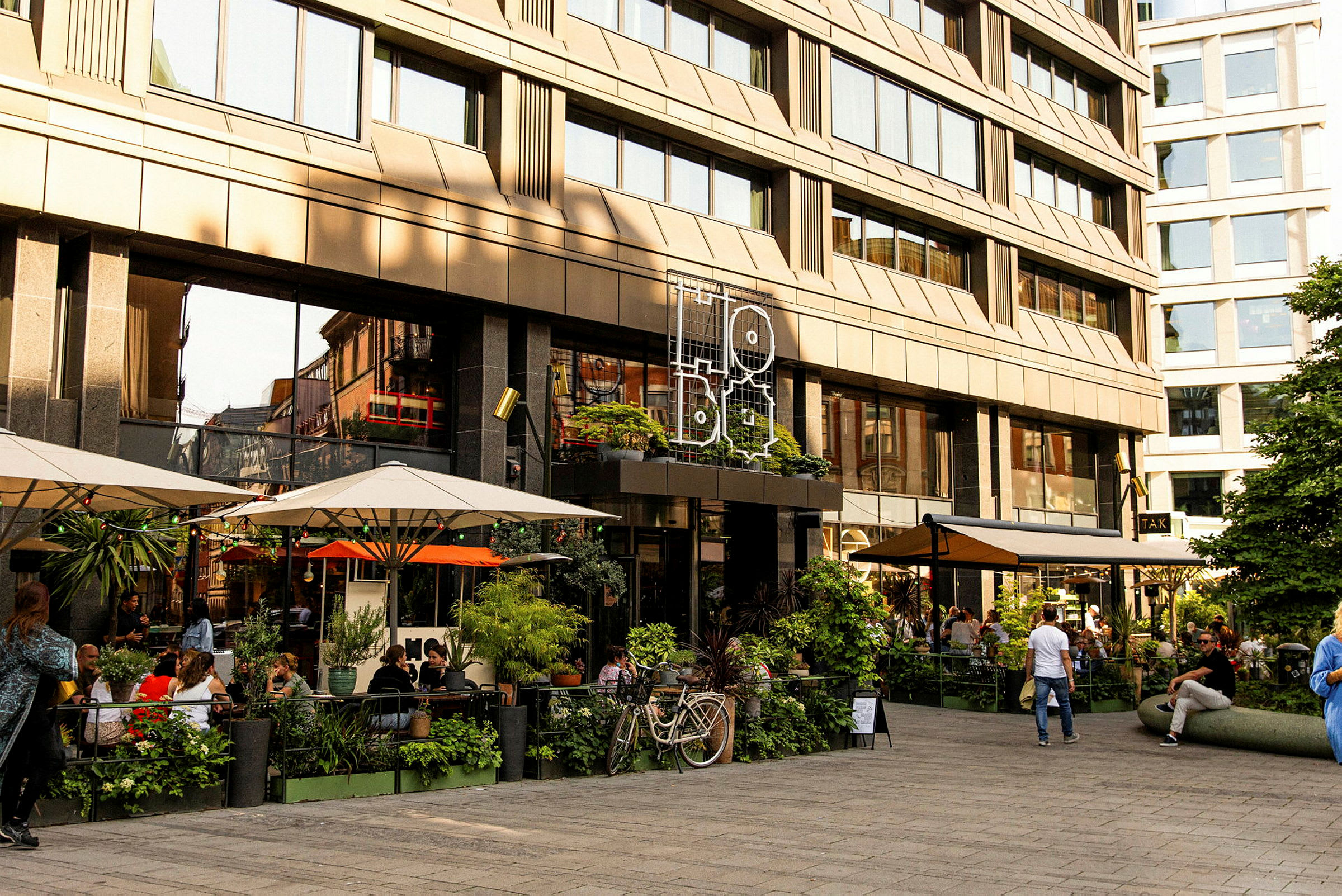 En udendørs servering foran en moderne bygning med store glasvinduer. (AI-genereret tekst)